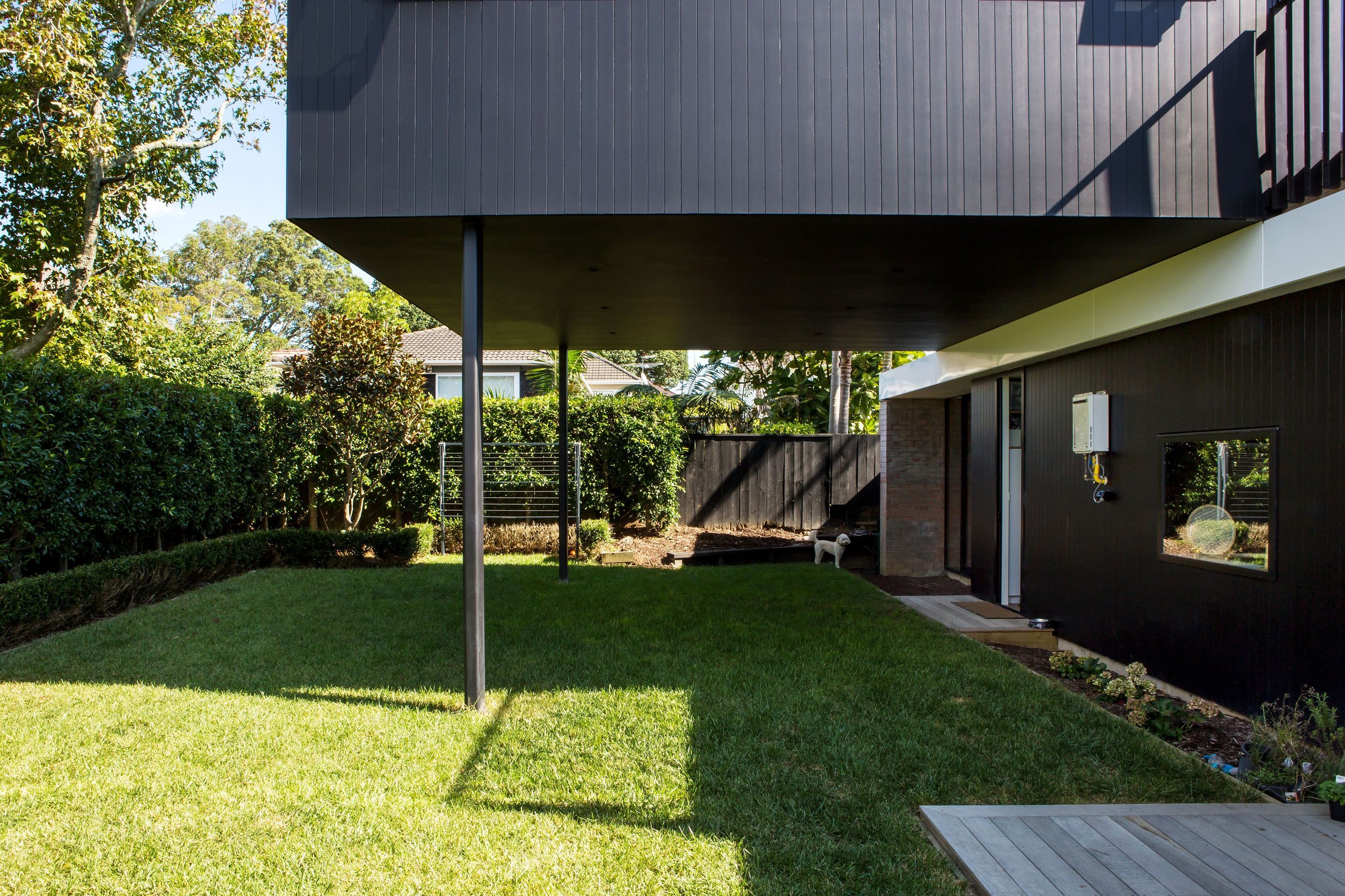 A flat lawn outside the kitchen partiially sits beneath the cantilevered upper storey.