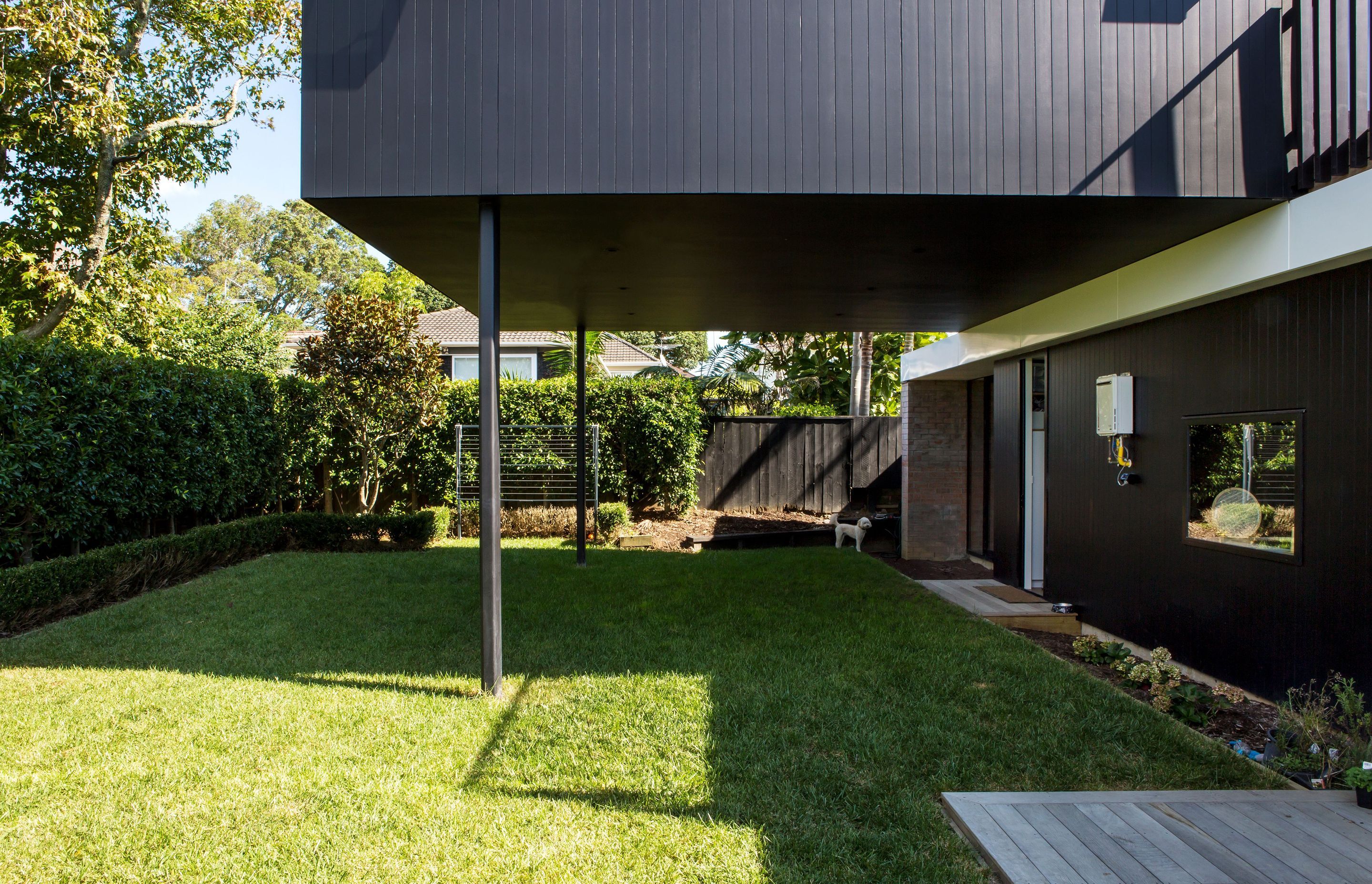 A flat lawn outside the kitchen partiially sits beneath the cantilevered upper storey.