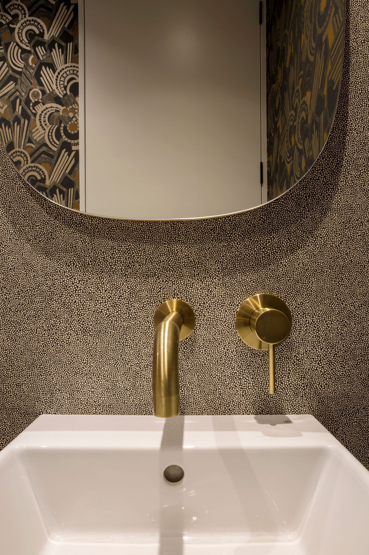 Brass tapware and retro wall coverings add personality to the powder room.