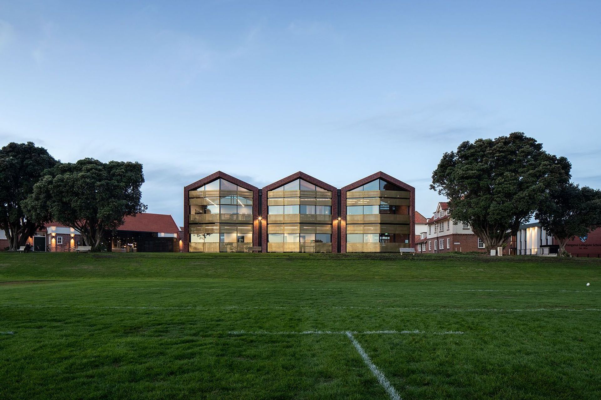 The new Administration Building seen from the number-one rugby ground are framed by a row of existing pohutakawa trees.