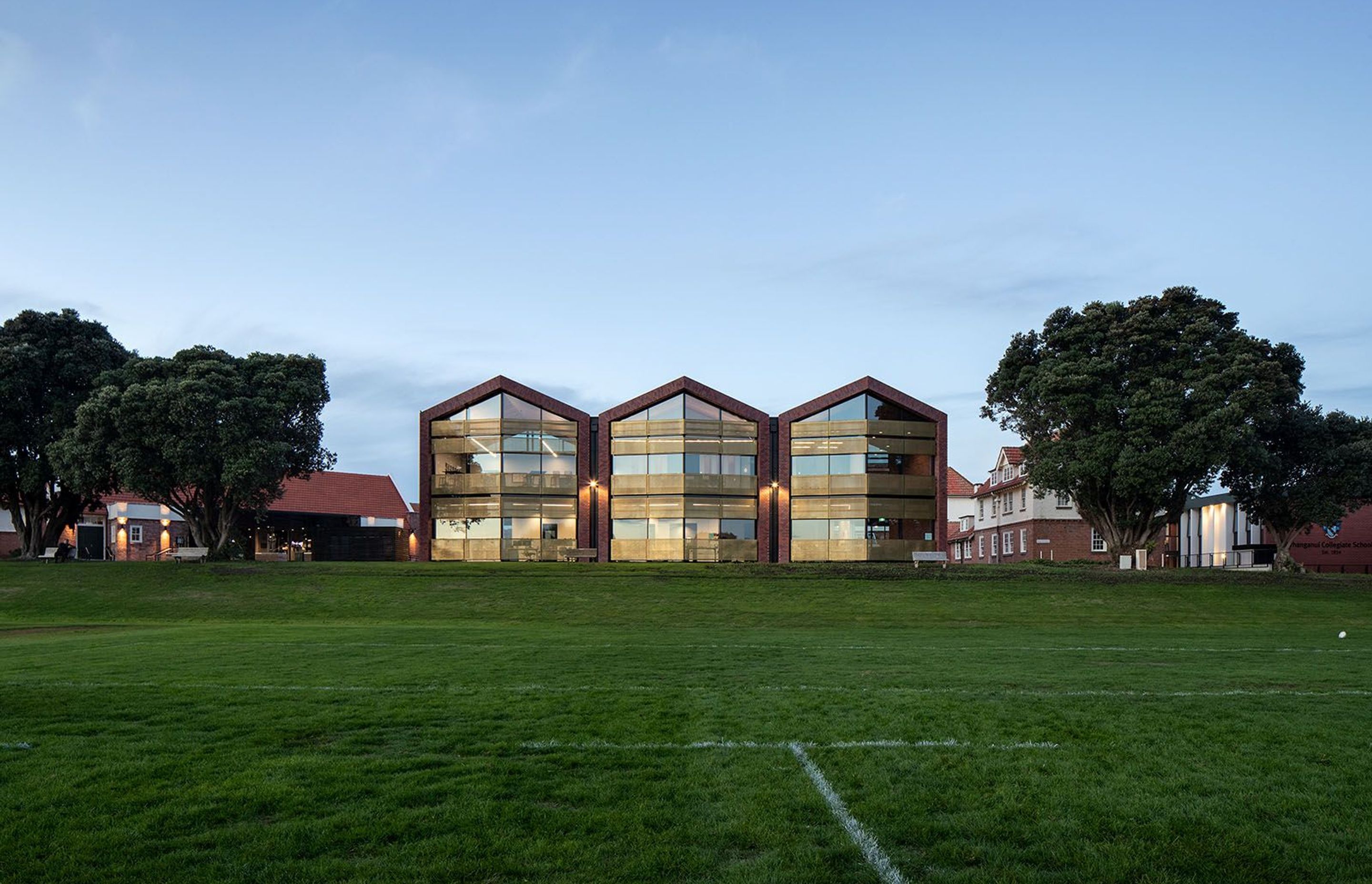 The new Administration Building seen from the number-one rugby ground are framed by a row of existing pohutakawa trees.