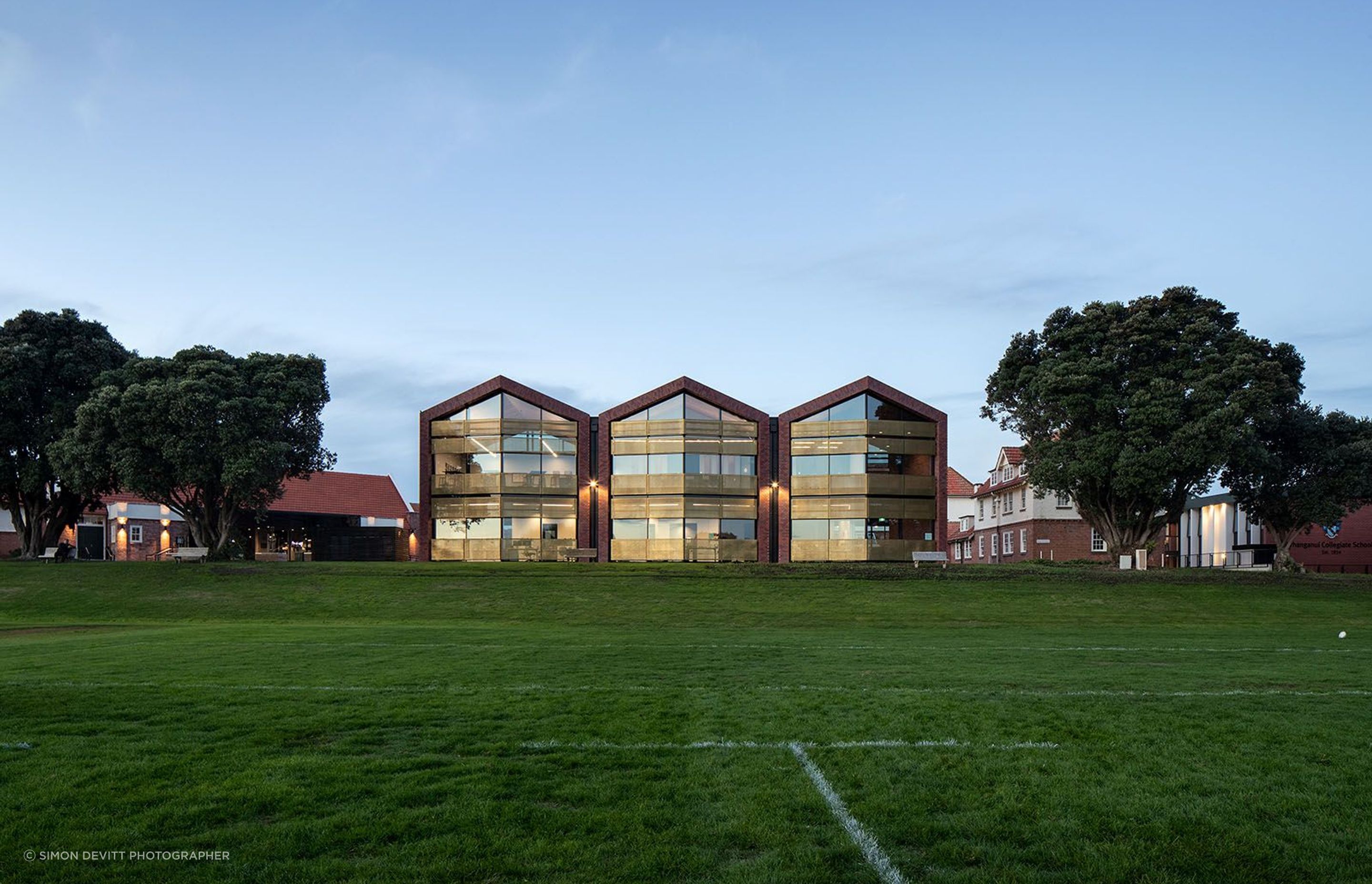 The new Administration Building seen from the number-one rugby ground are framed by a row of existing pohutakawa trees.