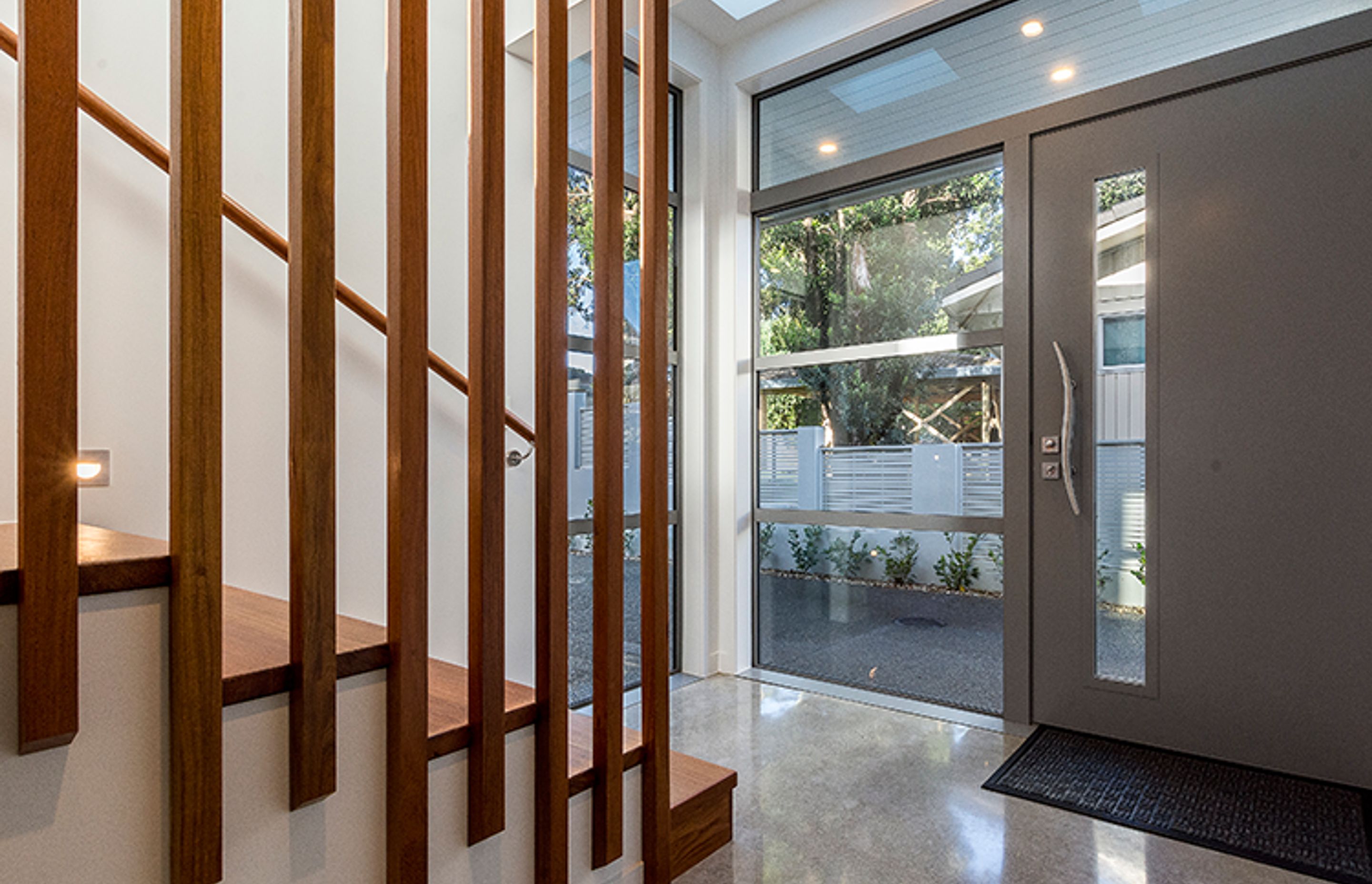 The entry features a hardwood staircase and cloakroom and polished concrete floors throughout. 