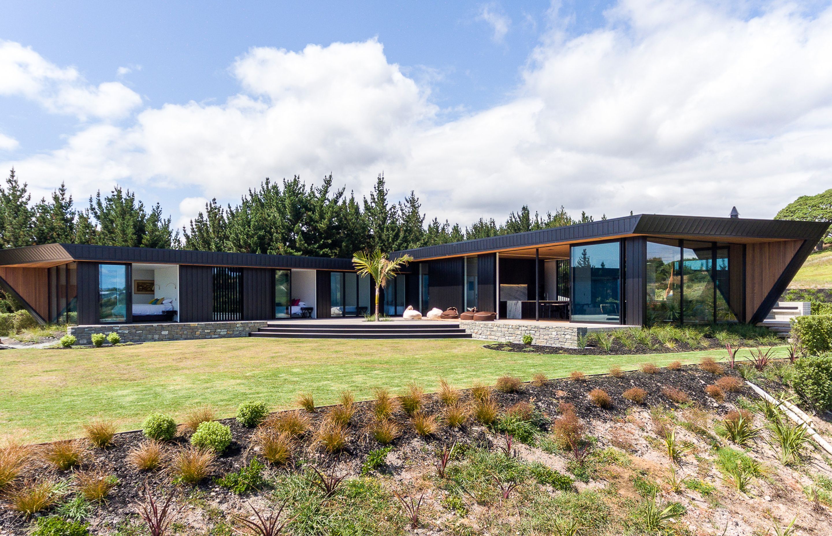 The house has a relatively simple, pinched L-shaped layout of two box forms with axial points leading east out to the Hen and Chicken Islands along the bedroom wing and north up the coast to Marsden Point and Whangarei Heads along the living wing