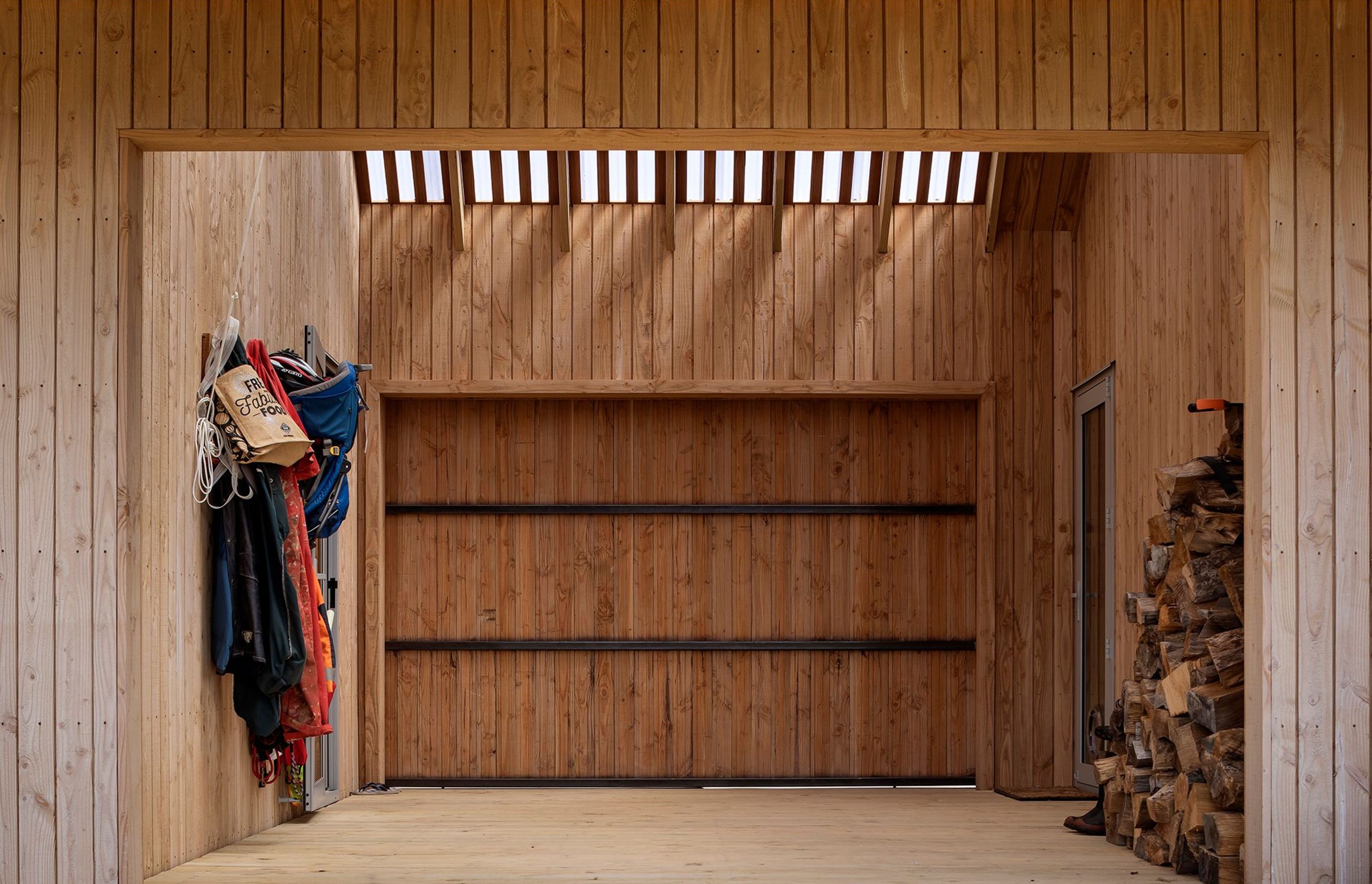 The timber cladding continues into the outdoor room, which is flooded with light through a polycarbonate roof.