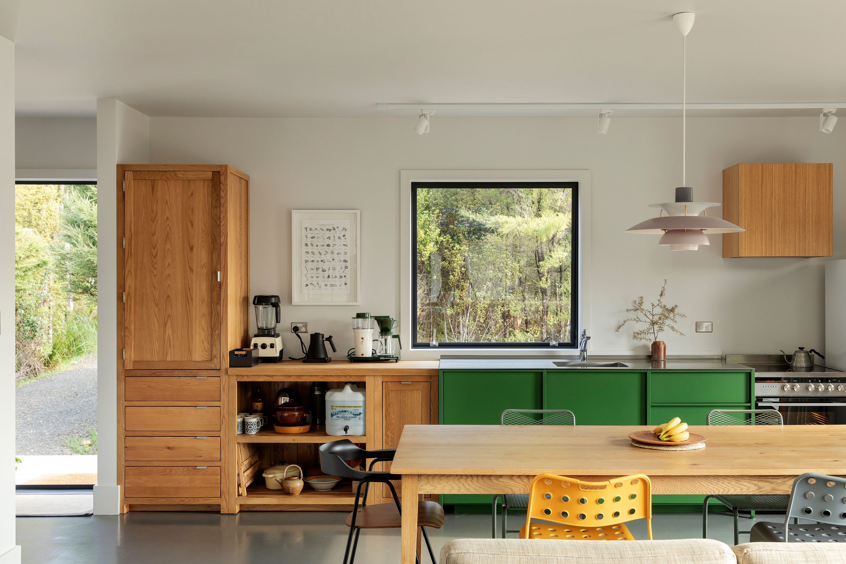 The kitchen is a simple medley of green and timber, while the dining table doubles as the client's main home wordspace. 