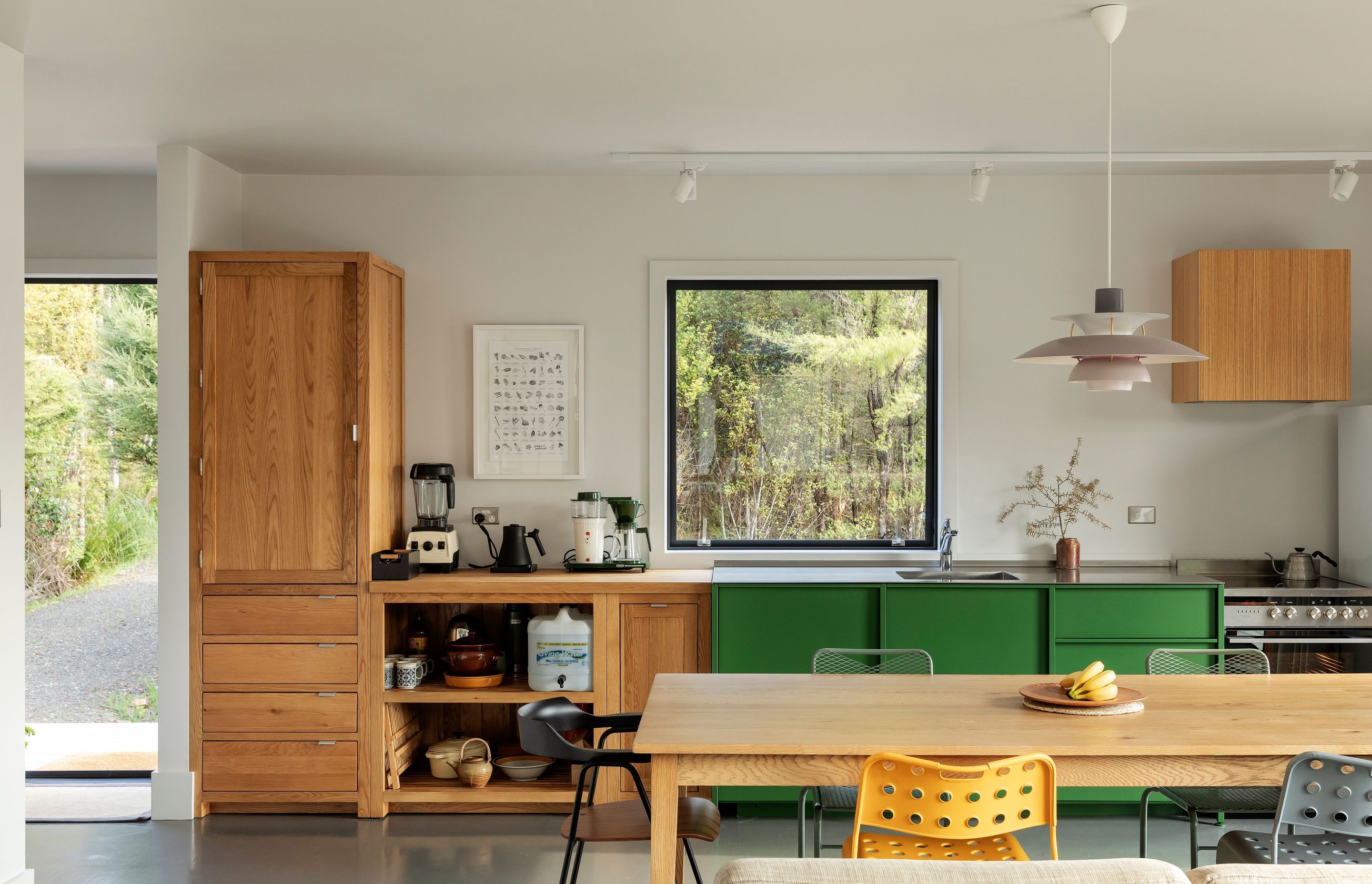 The kitchen is a simple medley of green and timber, while the dining table doubles as the client's main home wordspace.