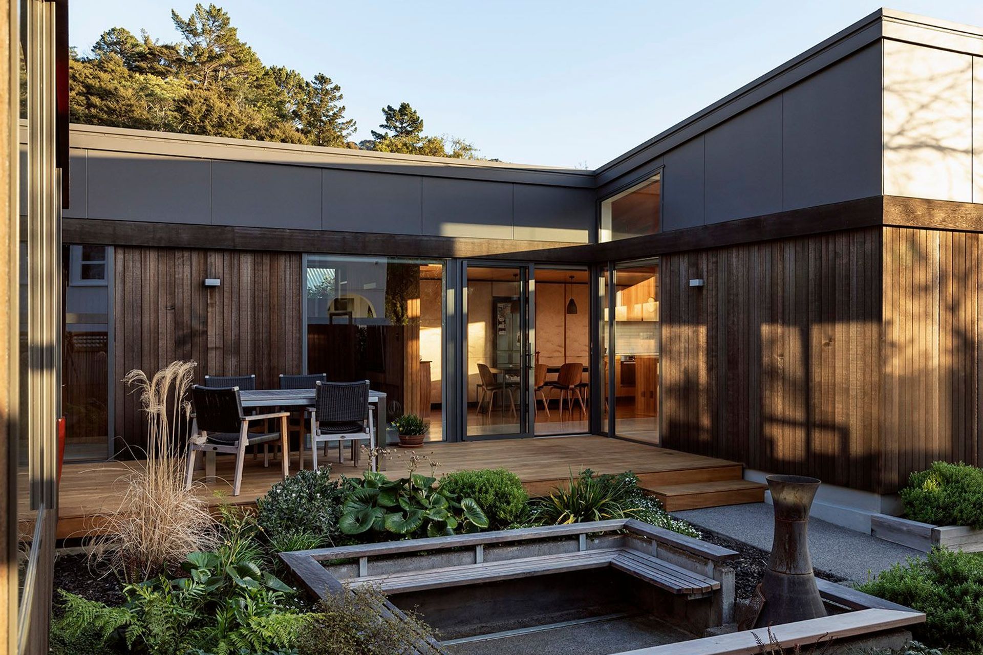 The house is clad in black cedar above which fibre cement board with negative joints caps the form—a response to the black beech that covers the surrounding hills.