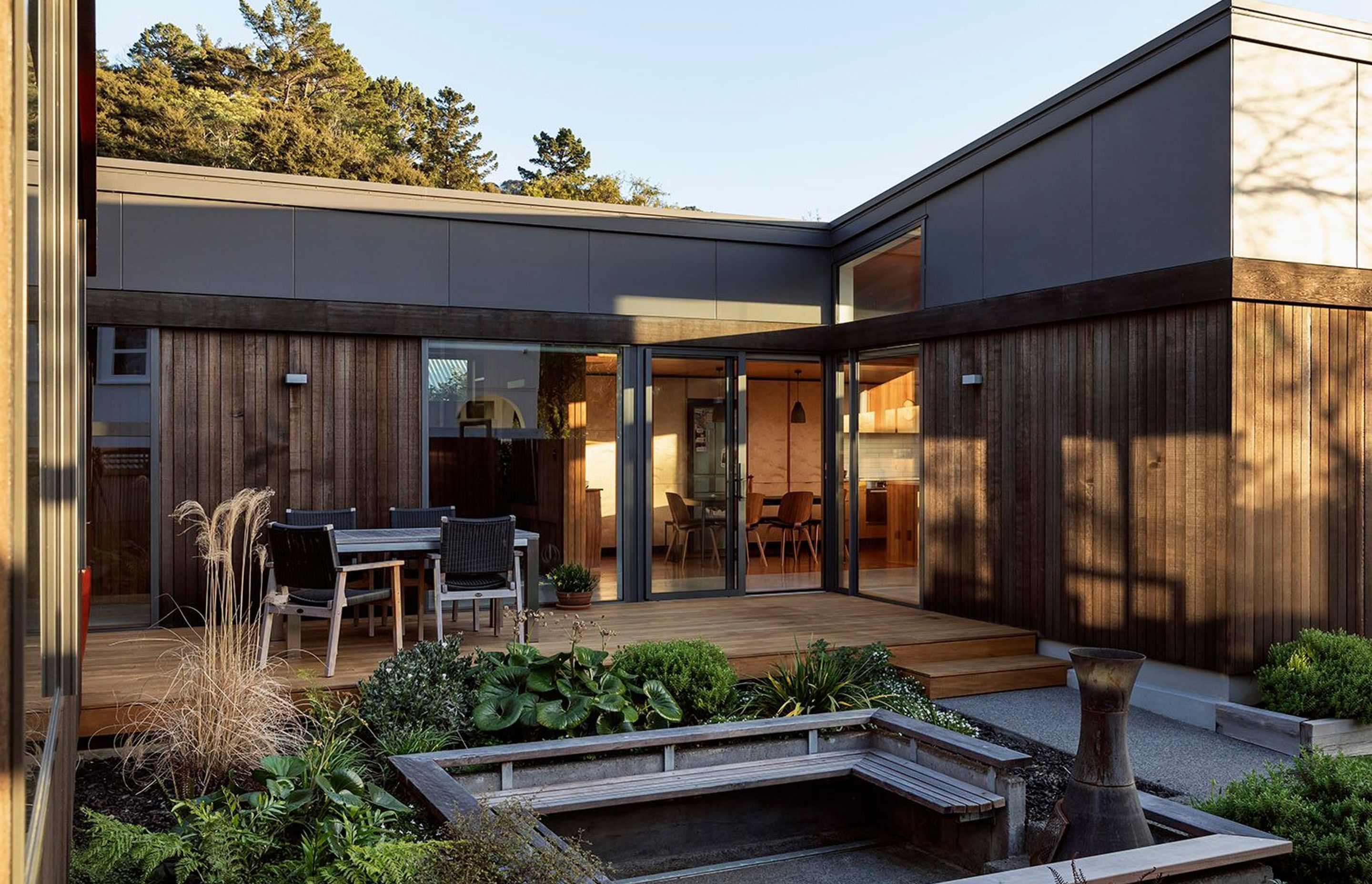 The house is clad in black cedar above which fibre cement board with negative joints caps the form—a response to the black beech that covers the surrounding hills.