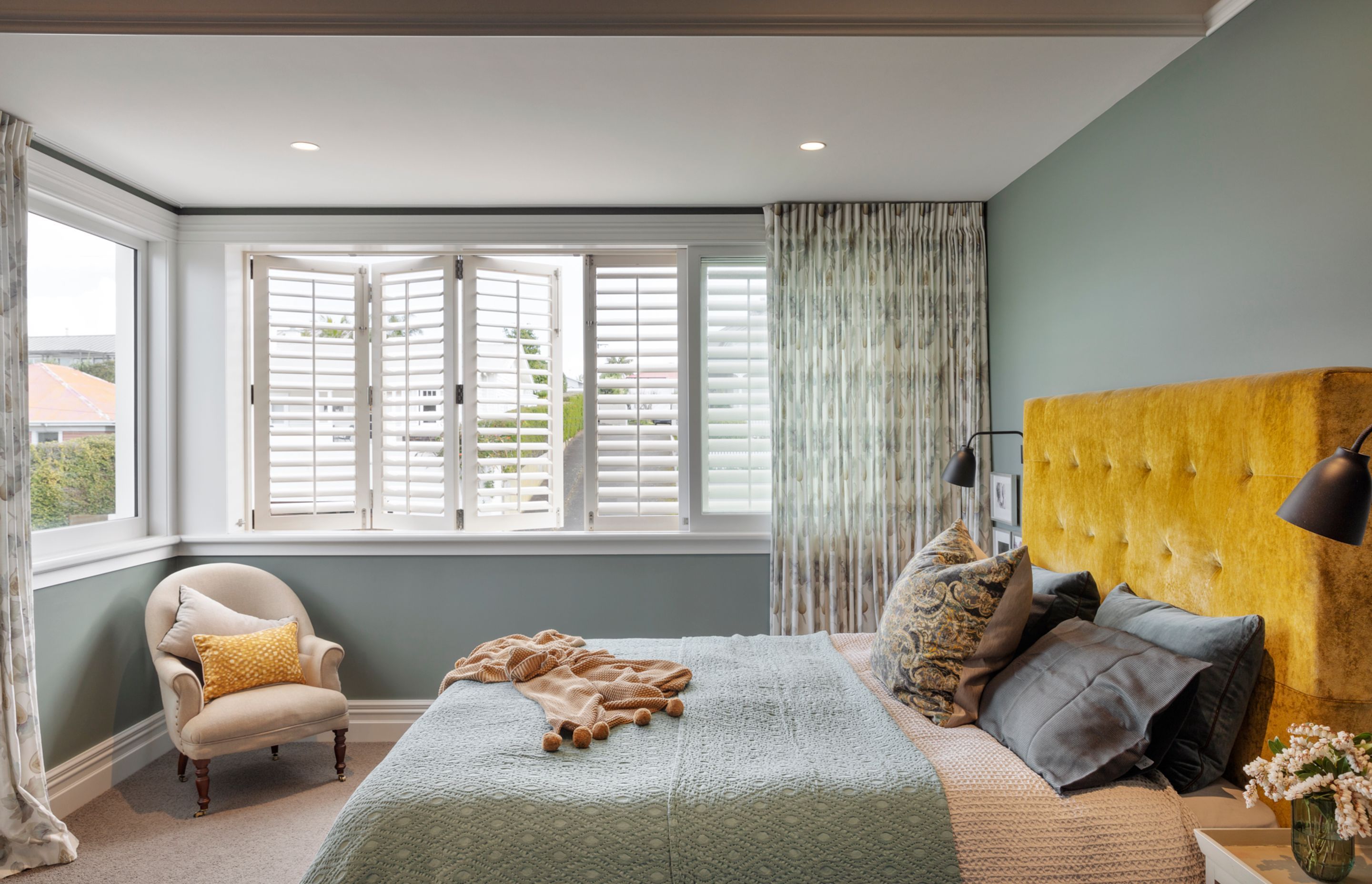 The master bedroom at the front of the house has shuttered windows and curtains for added privacy.