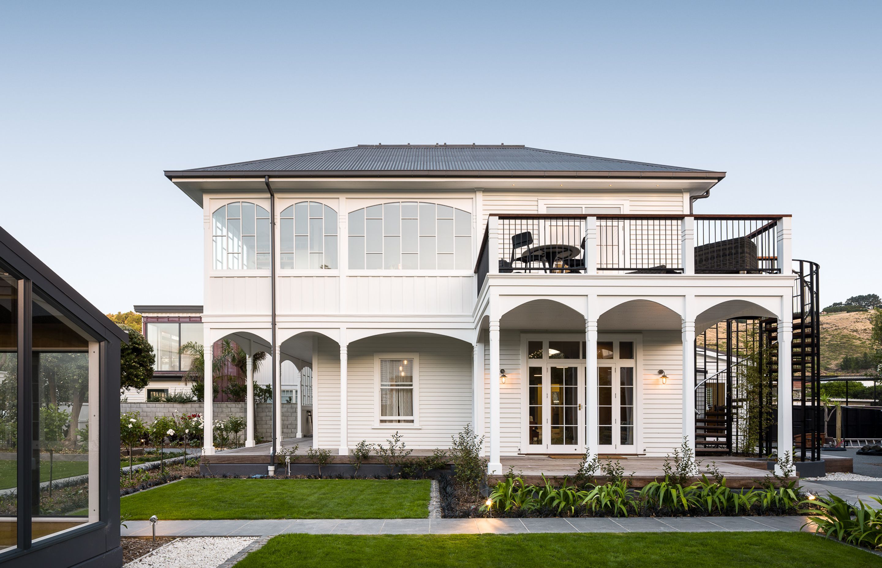 Esplanade House has an upstairs outdoor living area outlooking the sea across the road and a wraparound verandah with multiple arches.