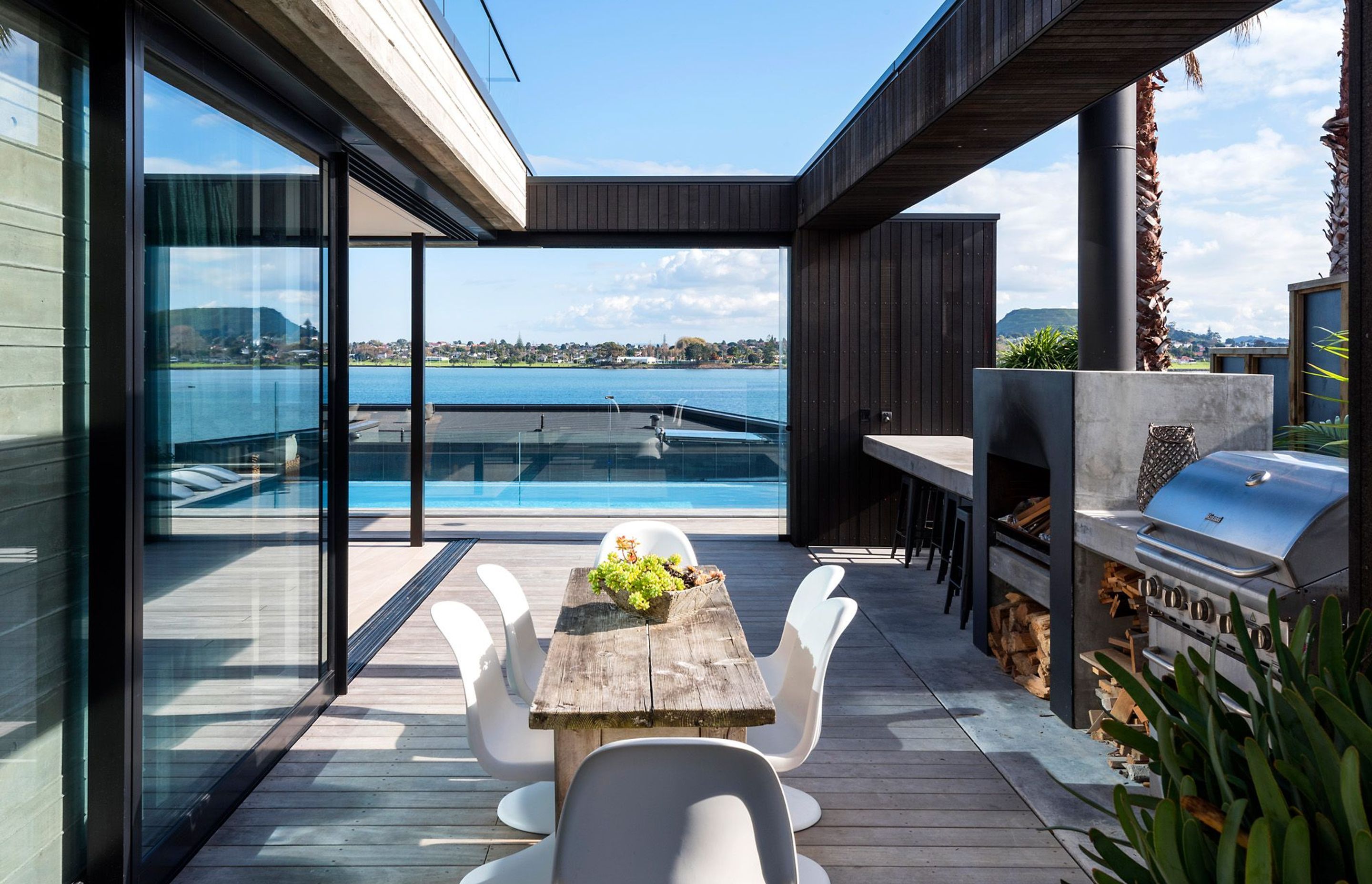 The outdoor kitchen and dining area has a built-in bar and fireplace. A sliding glass door at the end can be pulled across depending on the wind's direction.