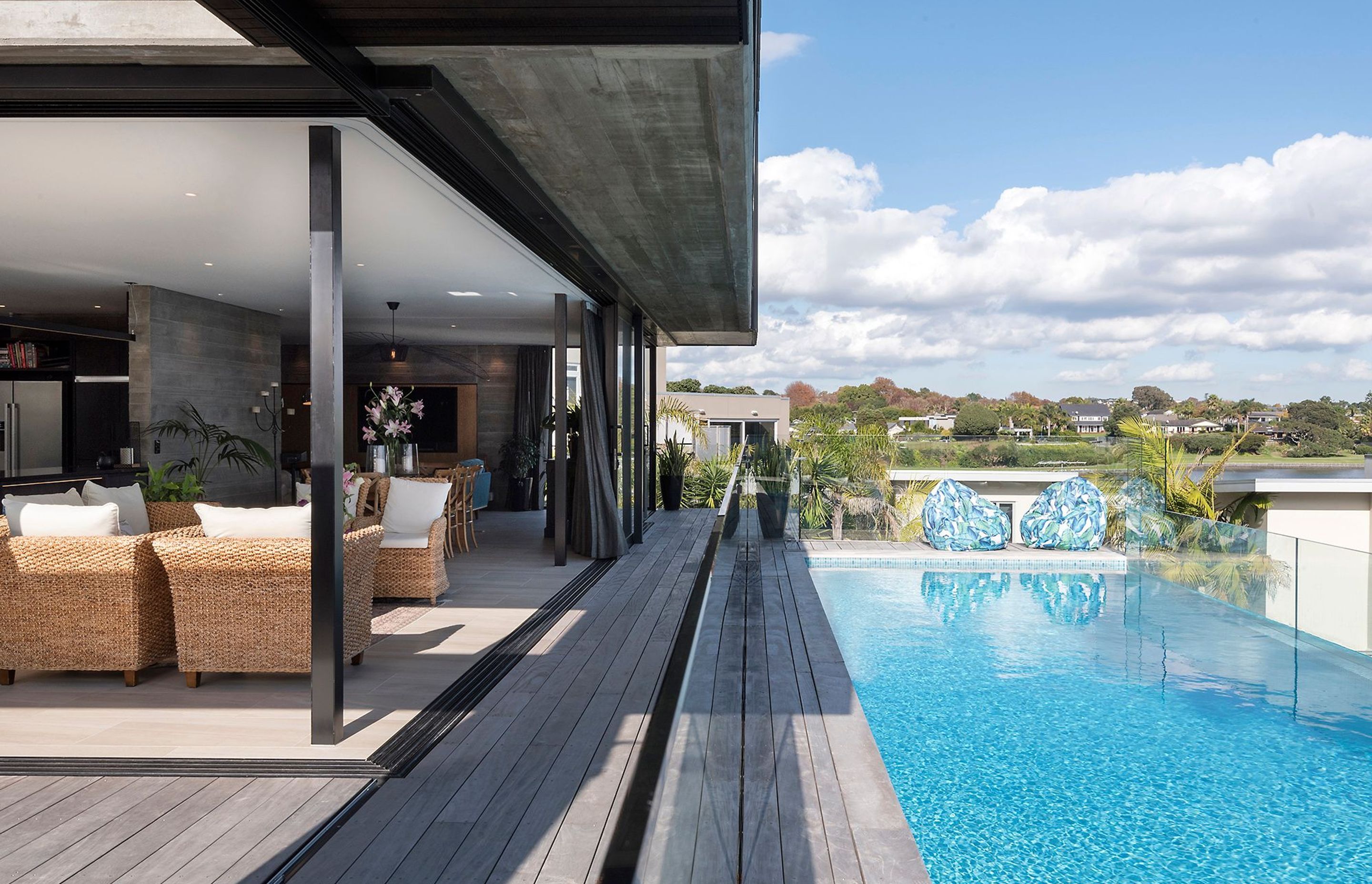 Sliding doors open up the two lounges and dining area on two sides, while a glass balustrade provides a transparent enclosure for the swimming pool.