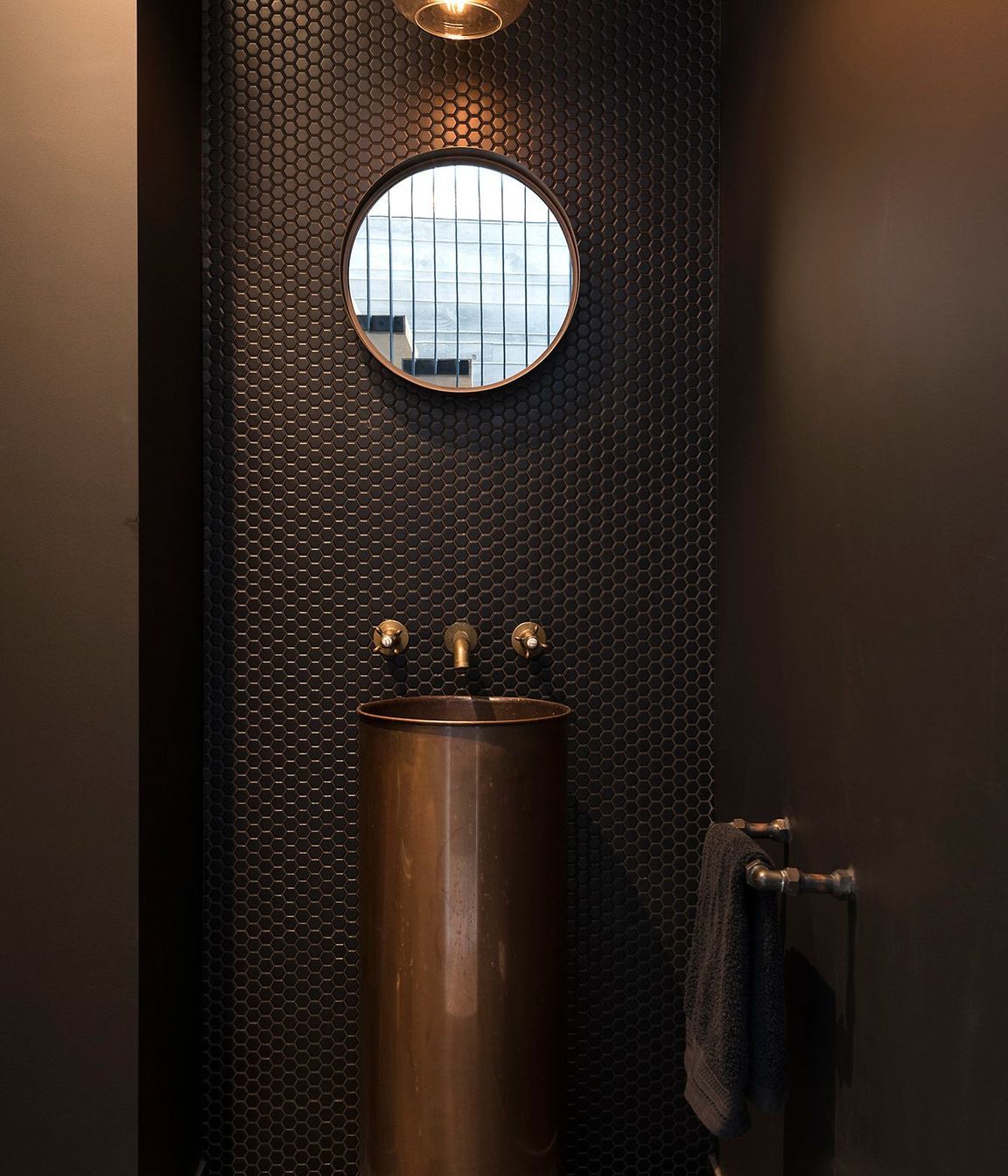 Tiling, tapware and pedestal basin in copper create a warm and elegant bathroom.