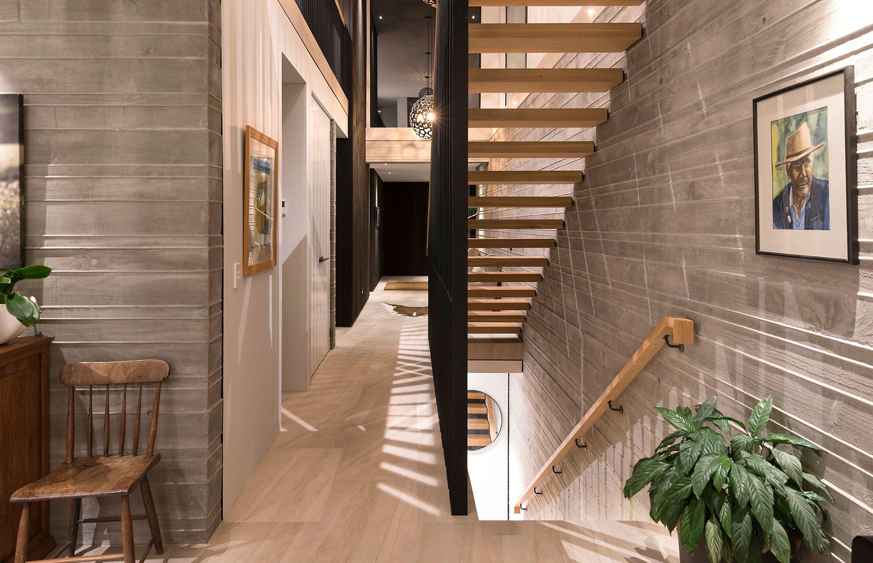The timber and metal stairwell connects three floors and is backed by a striking wall constructed in shuttered insitu concrete.