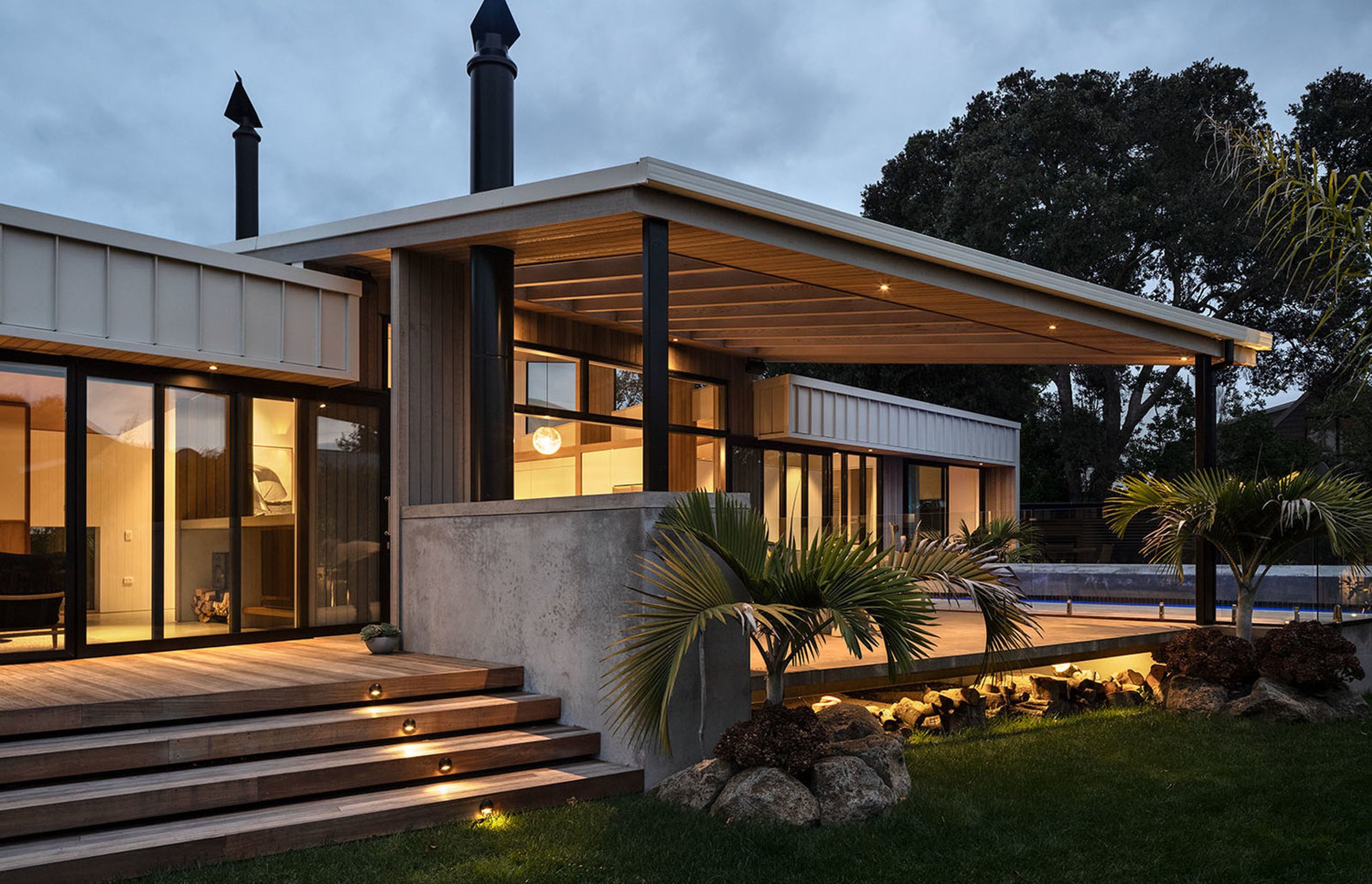 The outdoor living area is sheltered by a sail-like canopy with cedar-panelled soffit and a slatted shade.