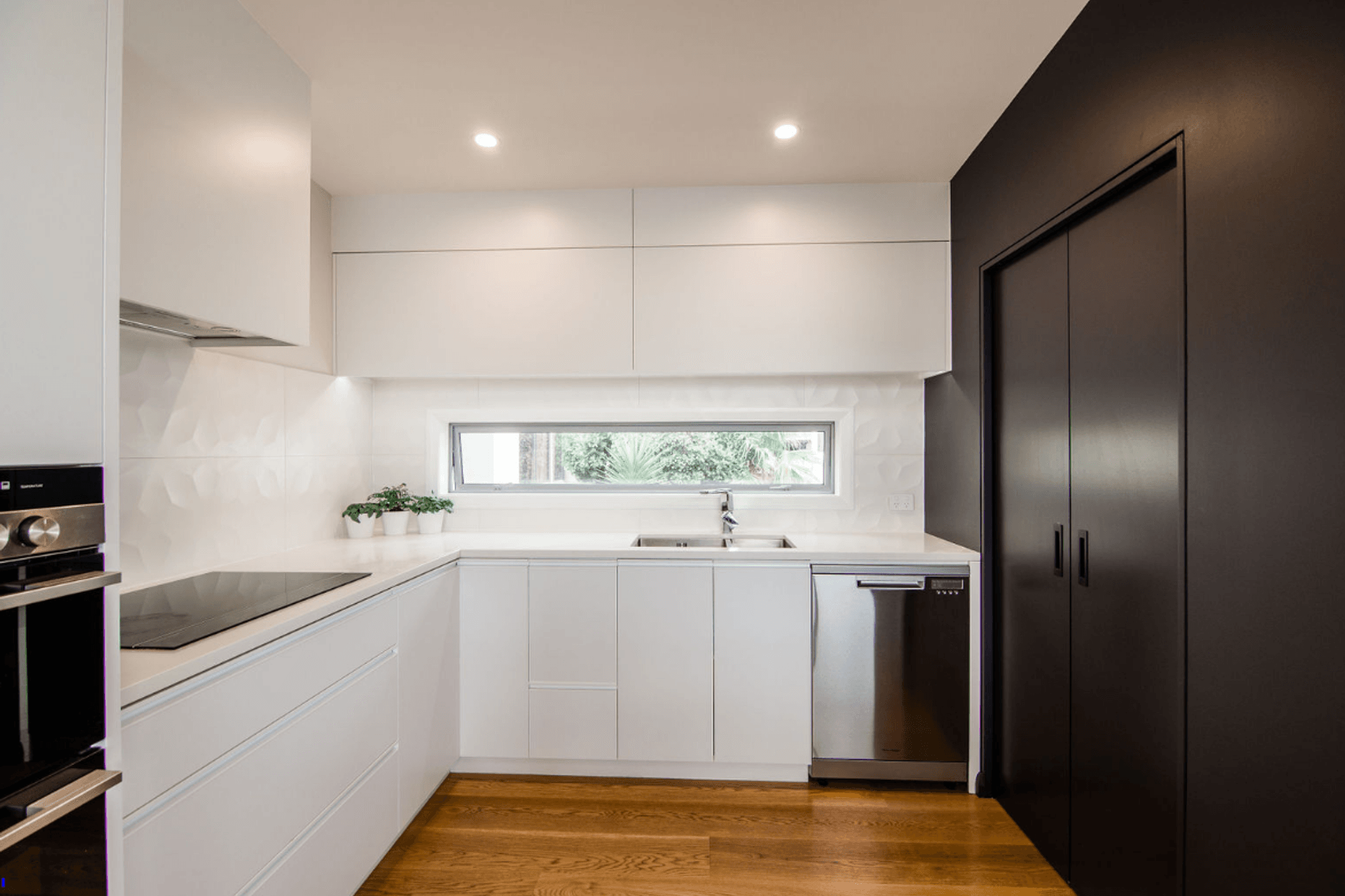 Sleek Black and White kitchen, the scullery is incorporated behind the black cavity sliders.