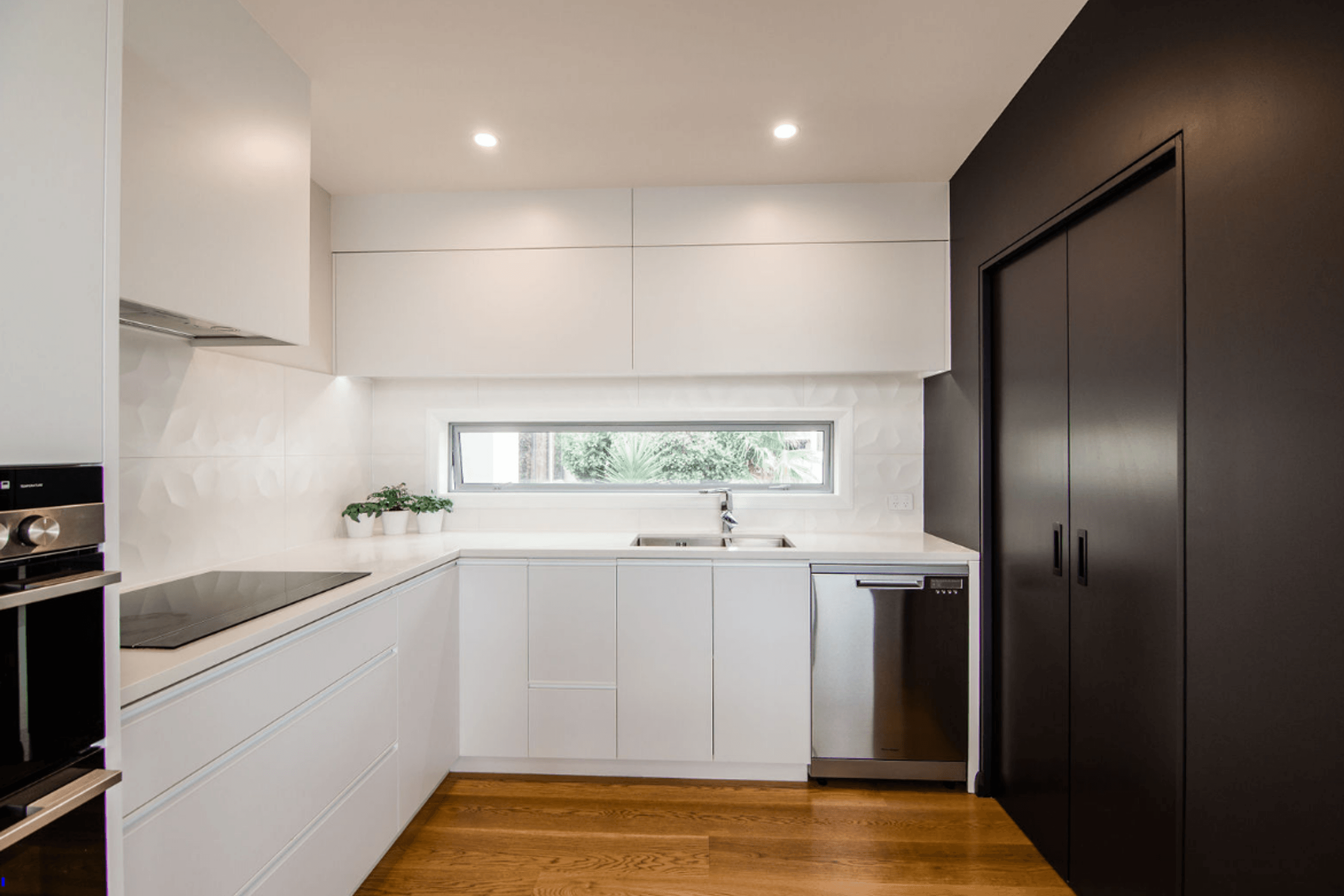 Sleek Black and White kitchen, the scullery is incorporated behind the black cavity sliders.