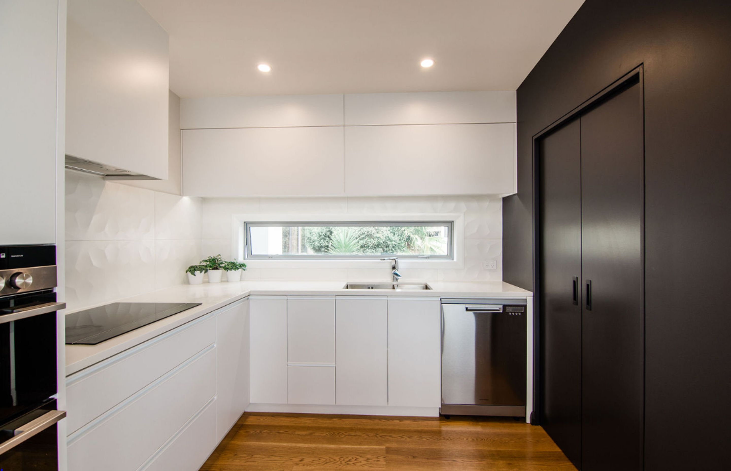 Sleek Black and White kitchen, the scullery is incorporated behind the black cavity sliders.
