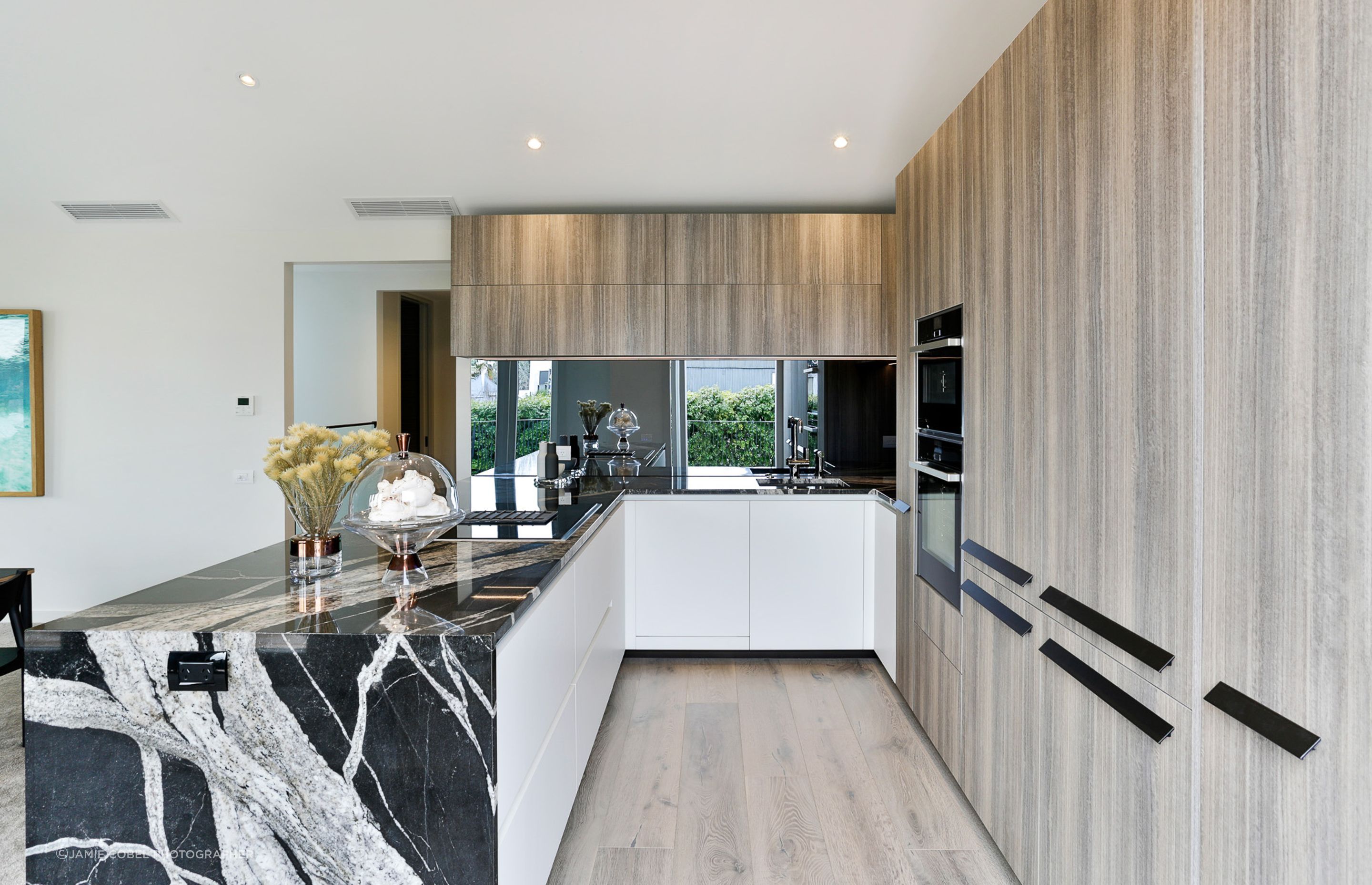 Exquisite feature Melamine Thermostructure Cabinetry by Arrital and lower Melamine Supermatt Bianco cabnetry by Arrital. With a Skyfall Granite top by Granite Workshop and Smokey Mirror splashback.