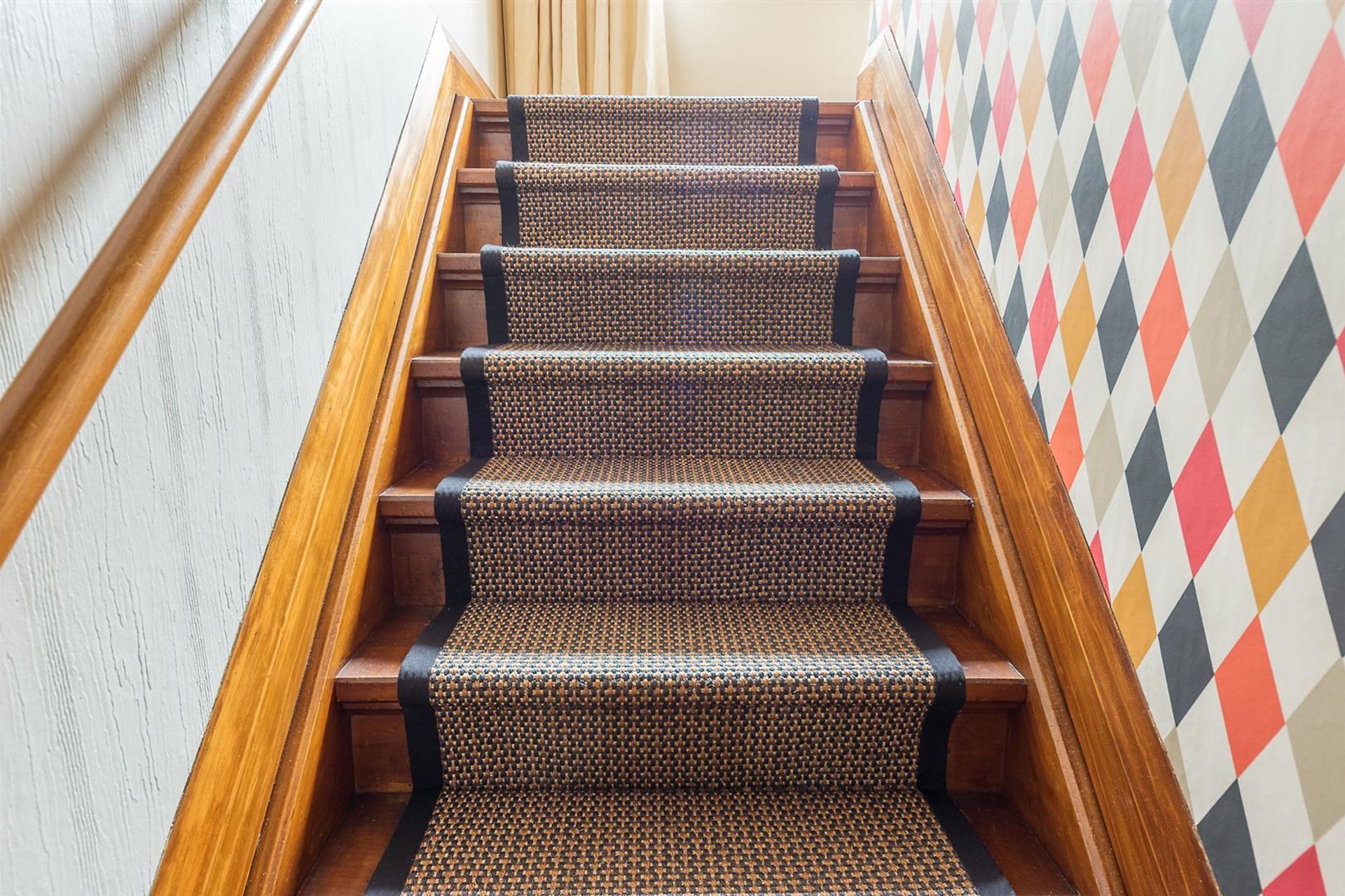 Stairs need as much attention to detail as any other room. Its in the detail we get a completed result....frame the stair runner with the black border. Continue the black element in the pattern of the wallpaper.