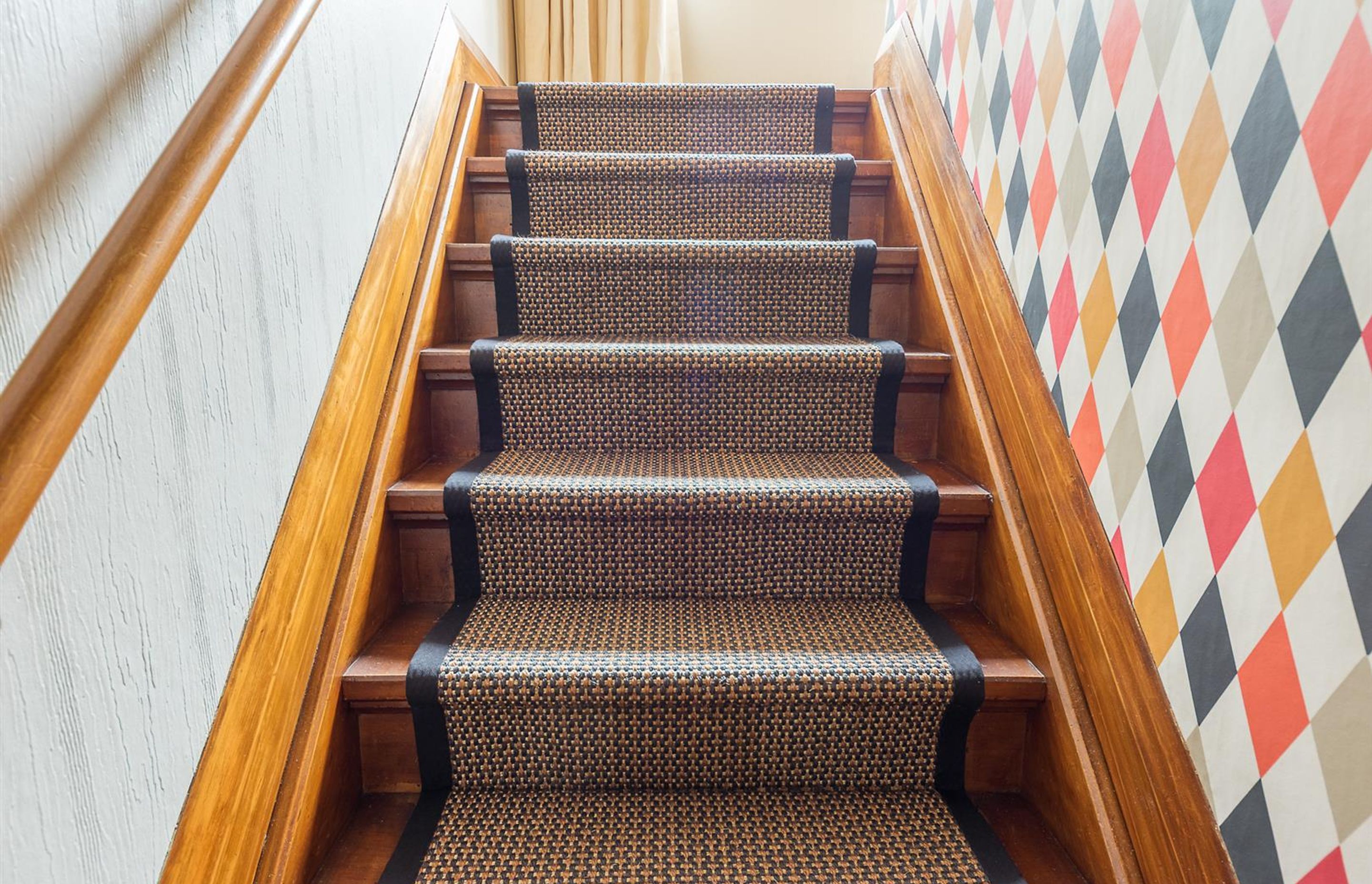 Stairs need as much attention to detail as any other room. Its in the detail we get a completed result....frame the stair runner with the black border. Continue the black element in the pattern of the wallpaper.