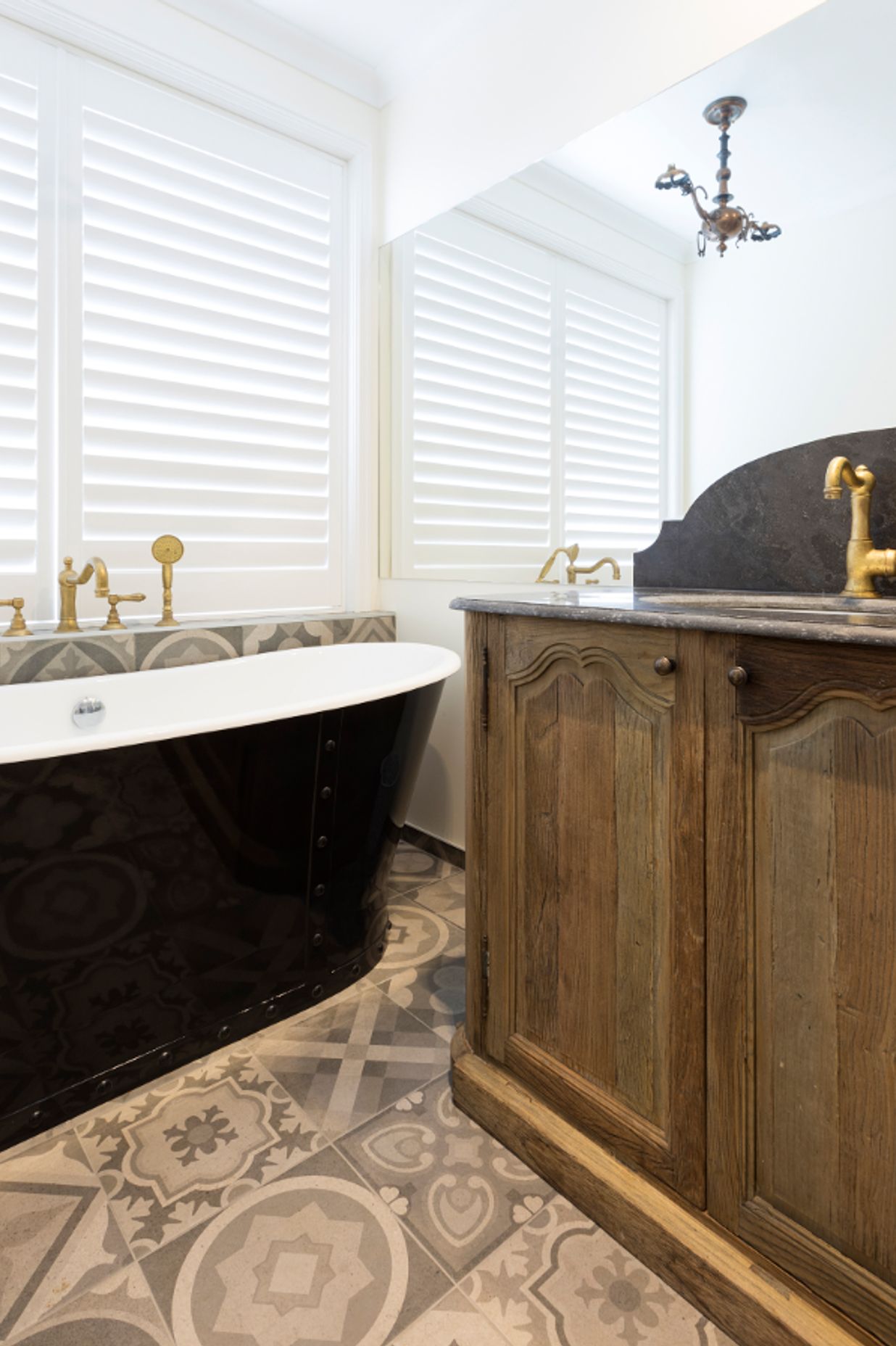 Freestanding bath with a vintage oak vanity and custom shutters 