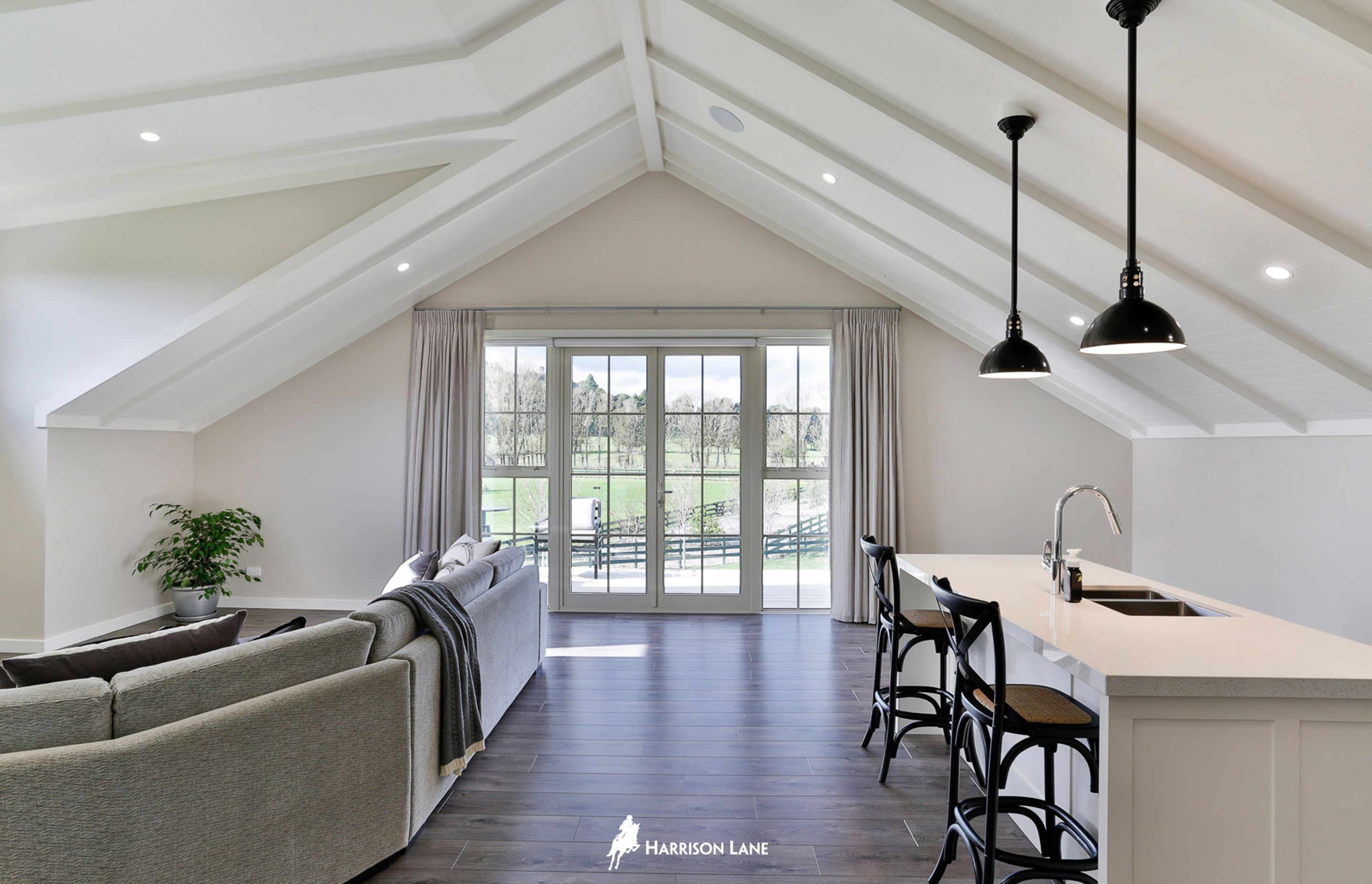 The upstairs lounge and bar area with French doors leading out to a glass balustrade-enclosed, north-facing deck