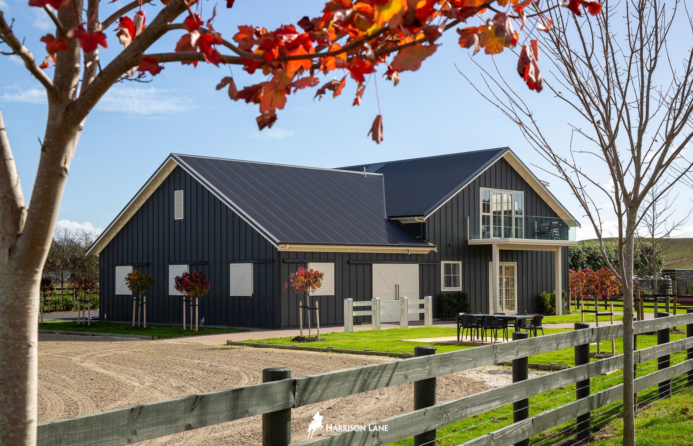 The barn is clad in charcoal grey-painted plywood and batten, with white details providing contrast.
