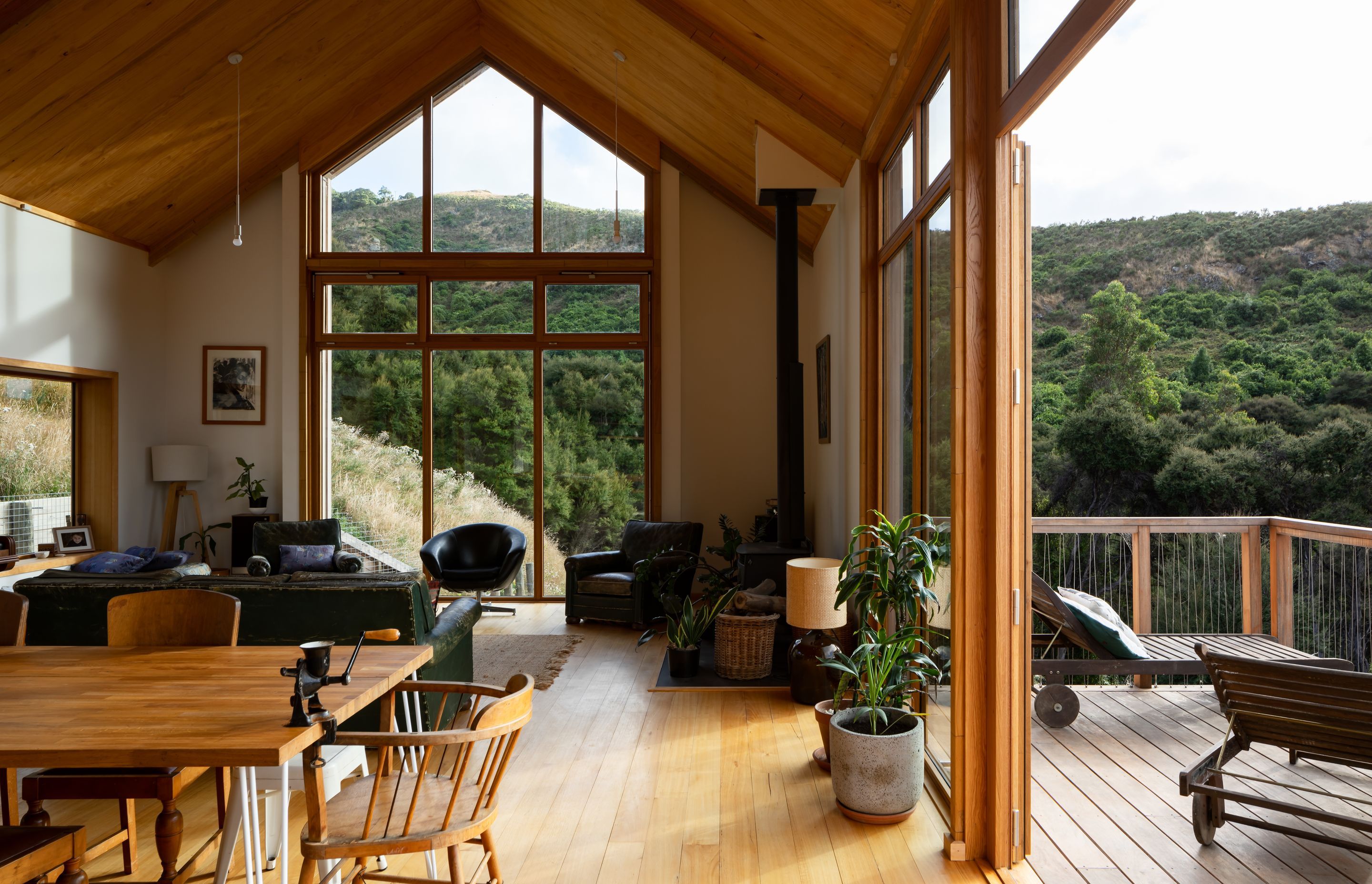 A cathedral-like gabled window draws light into the interior and frames the neighbouring bush-clad hill.