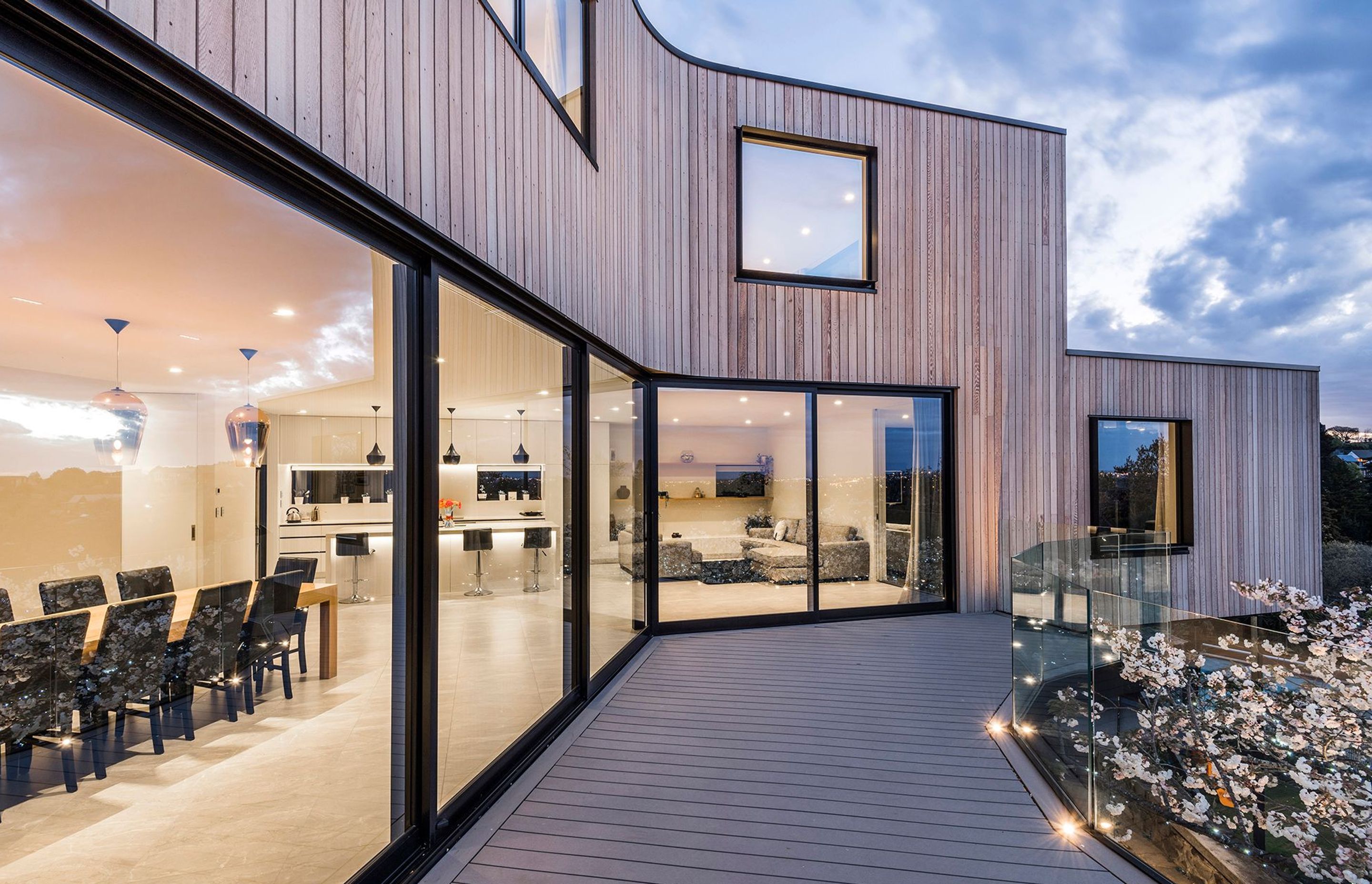 A modern light-filled living are has a kitchen and dining area in the middle, flanked by four distinct spaces for lounging.