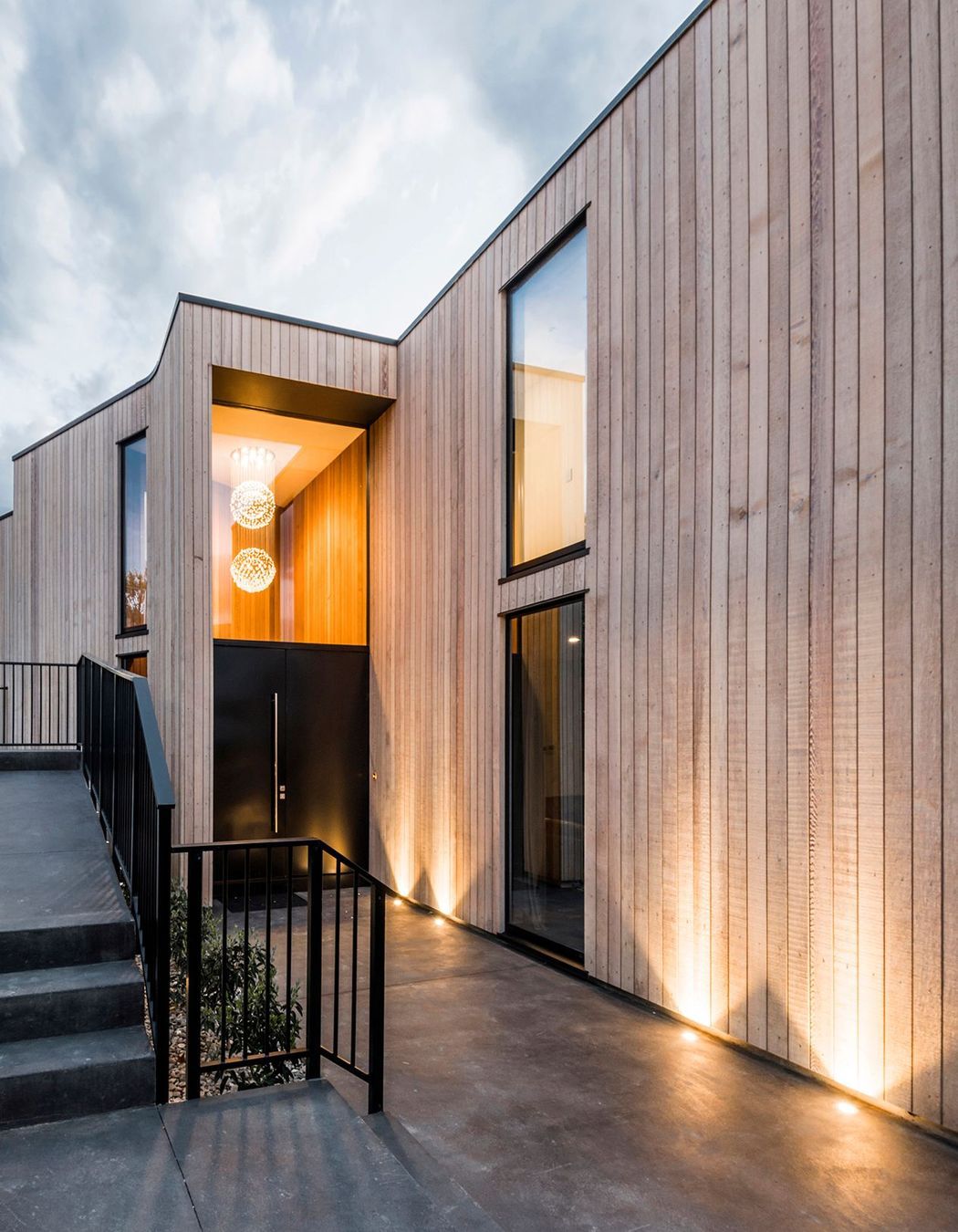 Stairs lead to the main entrance, following the contours of the steep terraced hillside site.