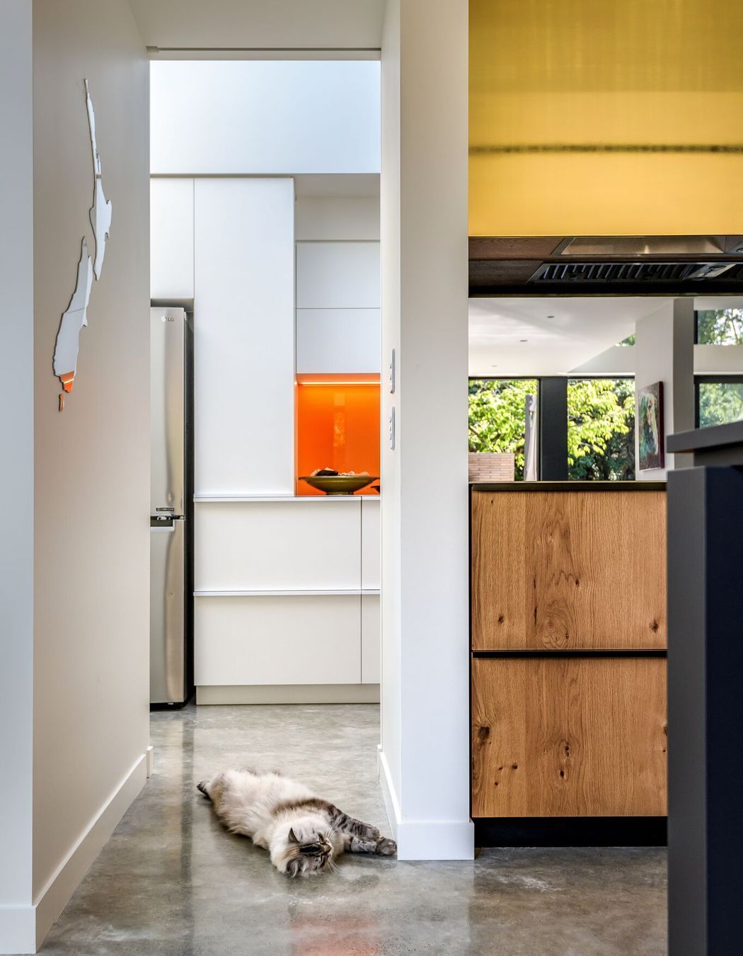 Looking through the kitchen to the scullery. Timber, gold and orange add warmth to the grey and white material palette.
