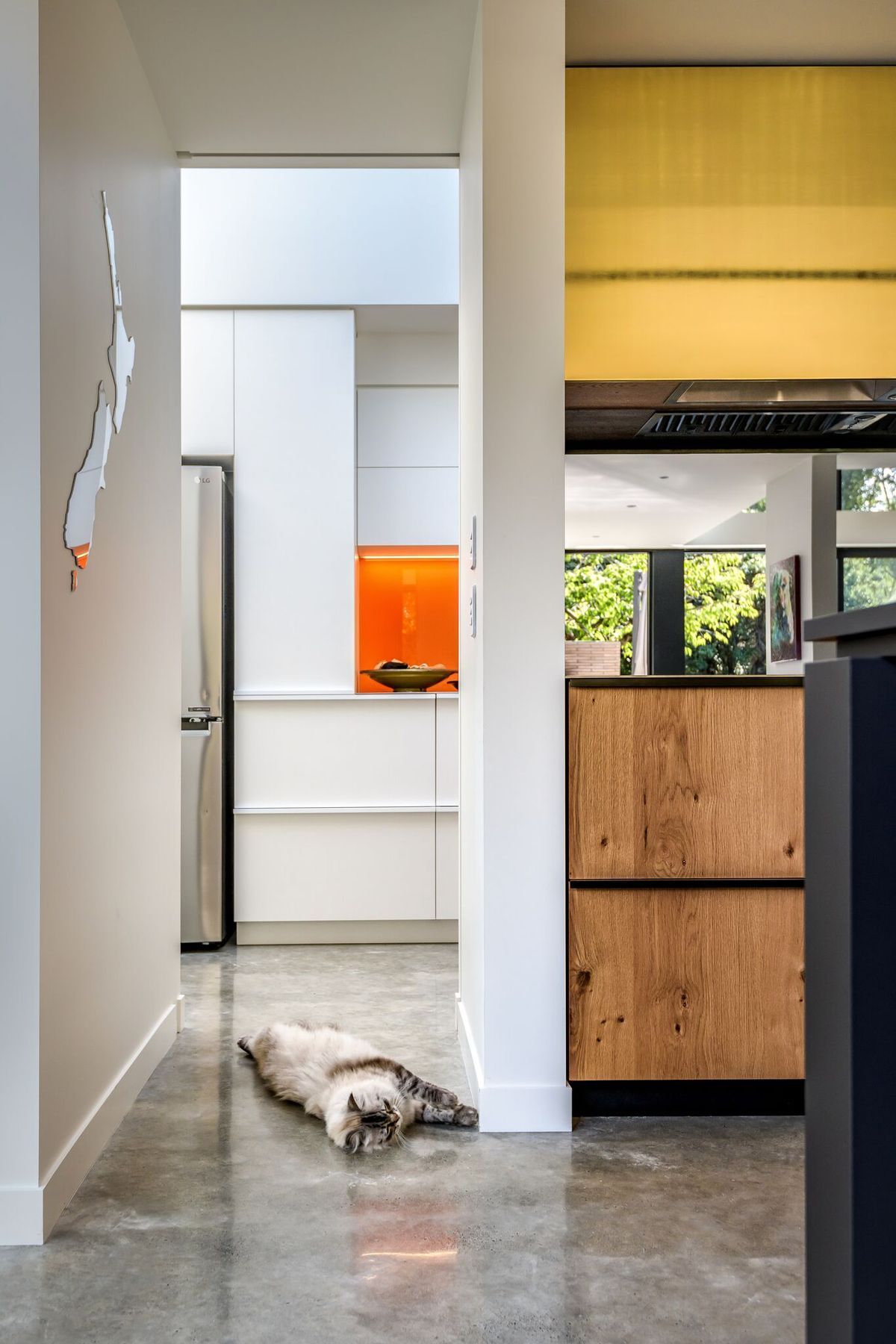 Looking through the kitchen to the scullery. Timber, gold and orange add warmth to the grey and white material palette.