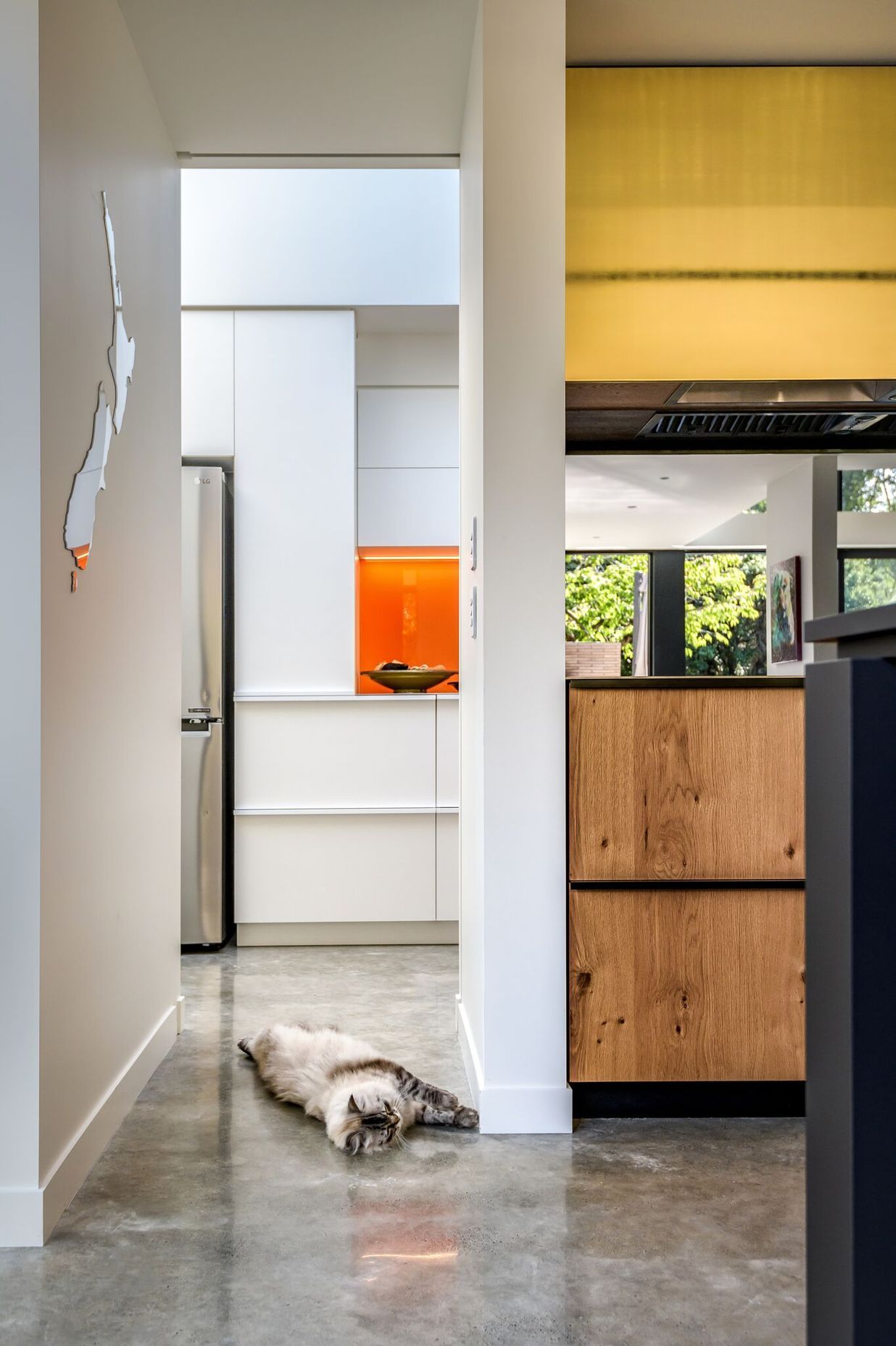 Looking through the kitchen to the scullery. Timber, gold and orange add warmth to the grey and white material palette.
