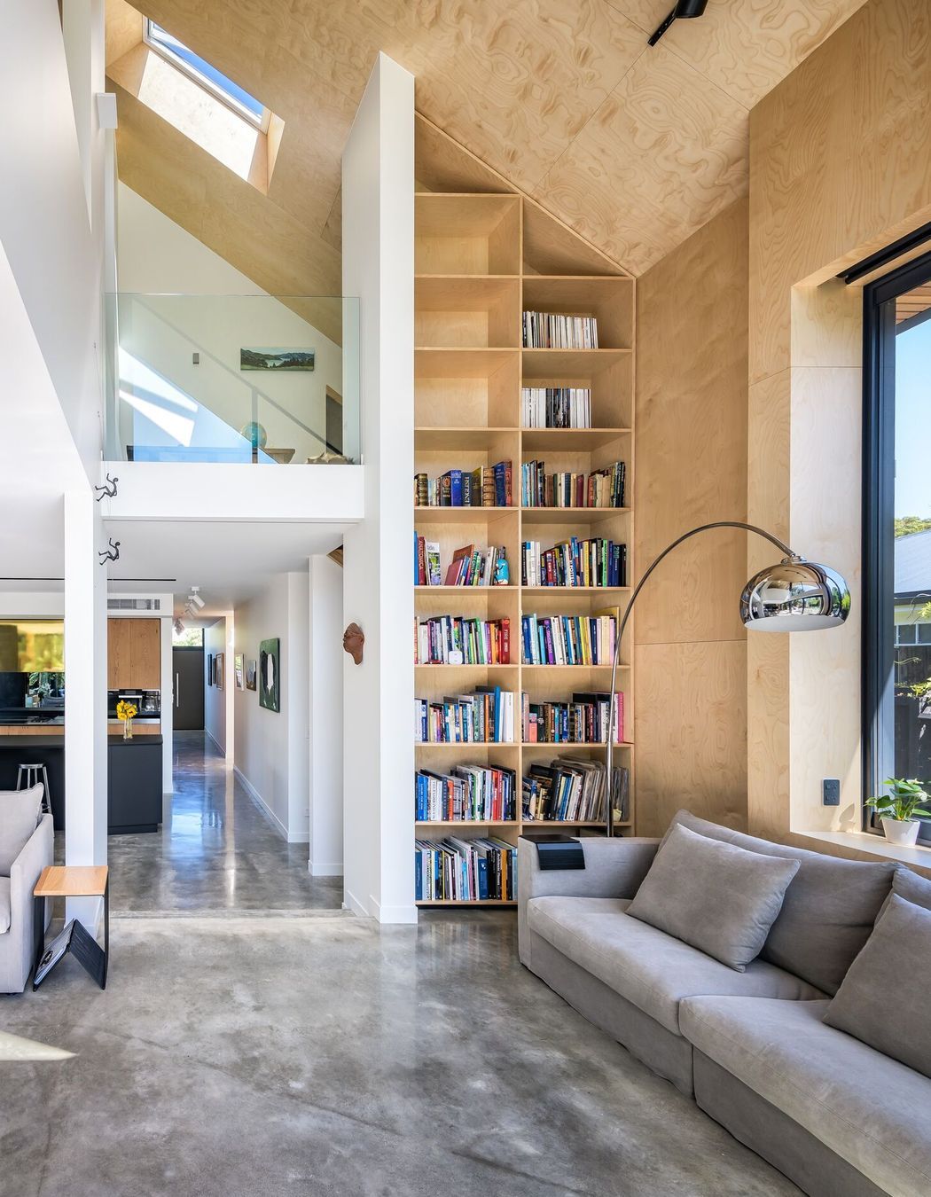 The double-height living space and bookcase leads south past the kitchen to the entry.
