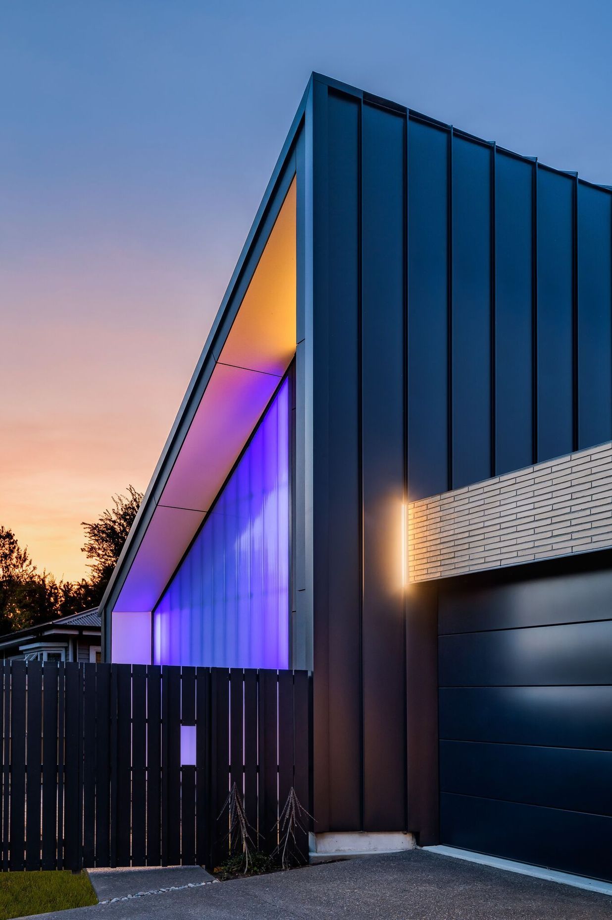 The street view shows the polycarbonate wall lit up at night and the flat metal wall of the half gable form. All photography by Anthony Turnham.