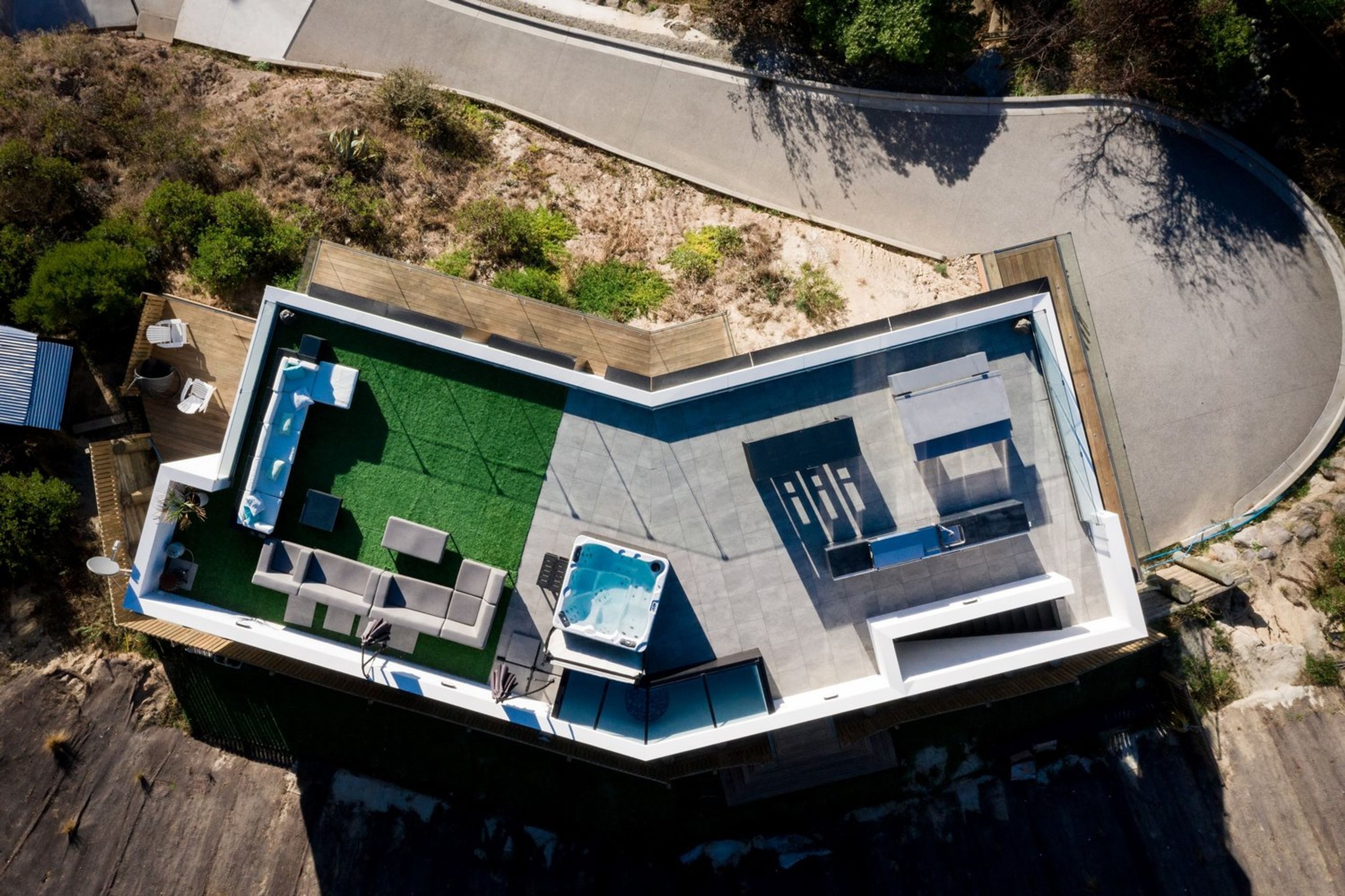 A bird's eye view of the site plan shows the outdoor lounge area on astroturf. the spa pool and an outdoor kitchen and dining area leading to the staircase.