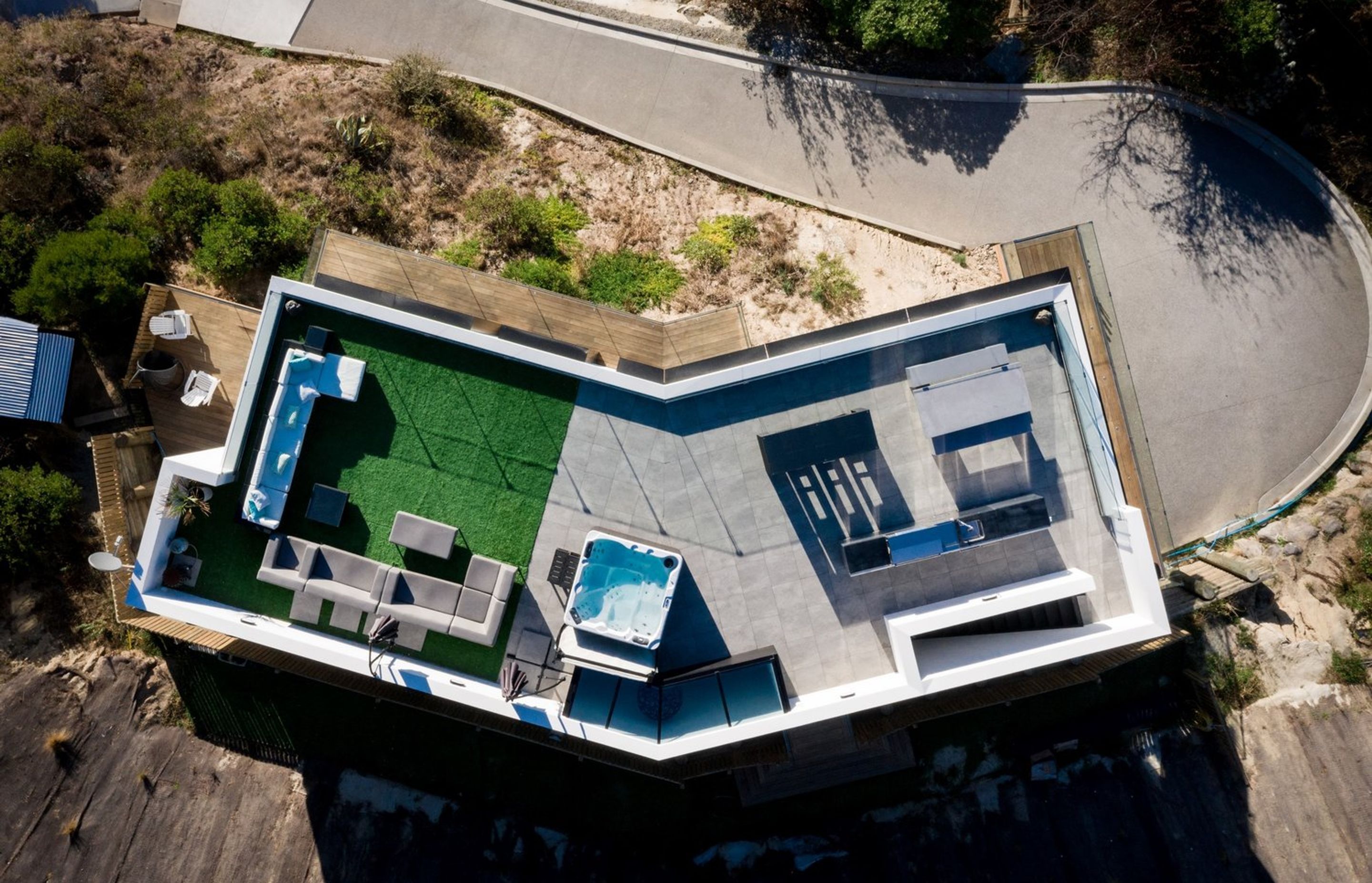 A bird's eye view of the site plan shows the outdoor lounge area on astroturf. the spa pool and an outdoor kitchen and dining area leading to the staircase.