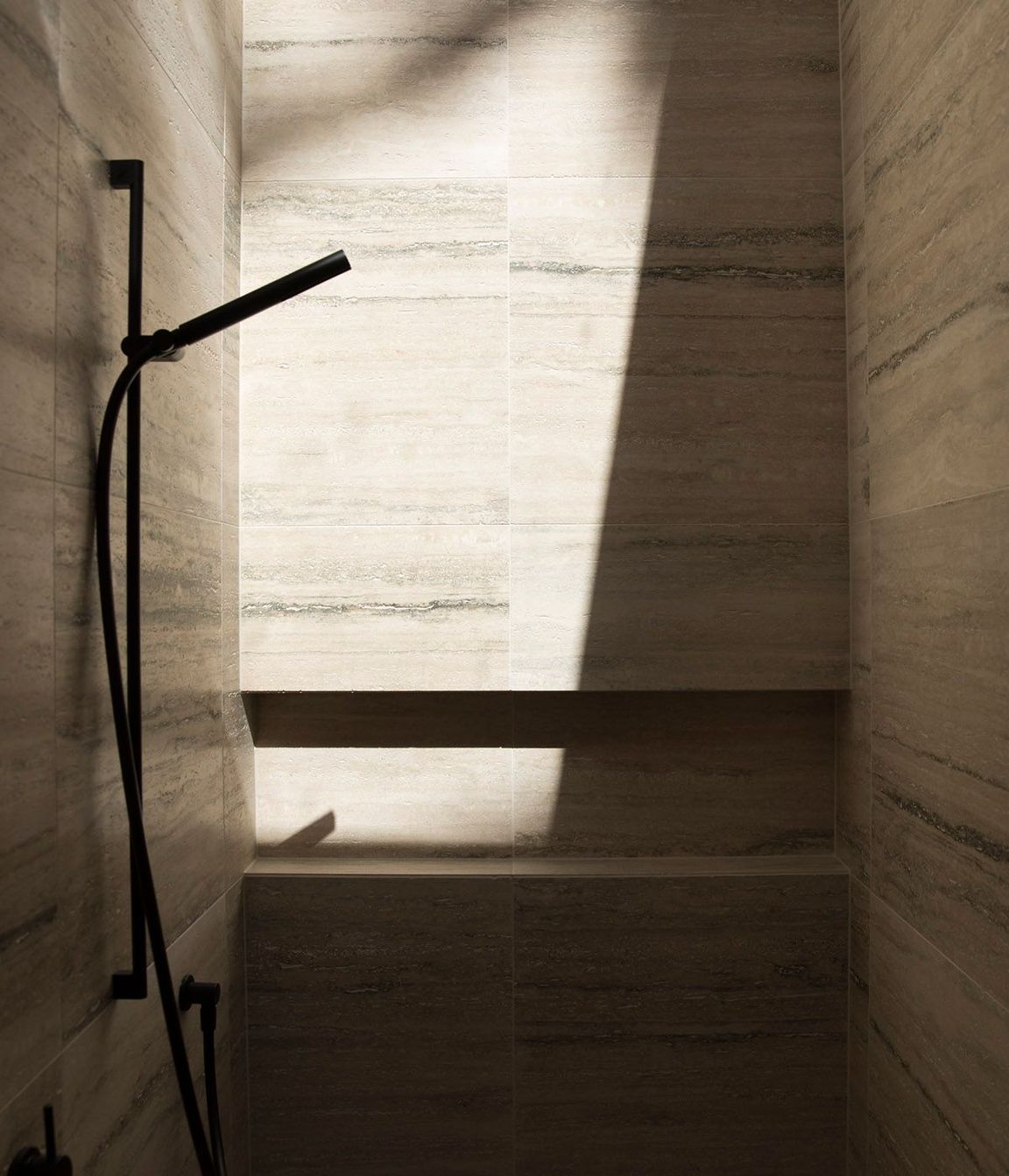 This travertine-lined shower is lit from above via a skylight.