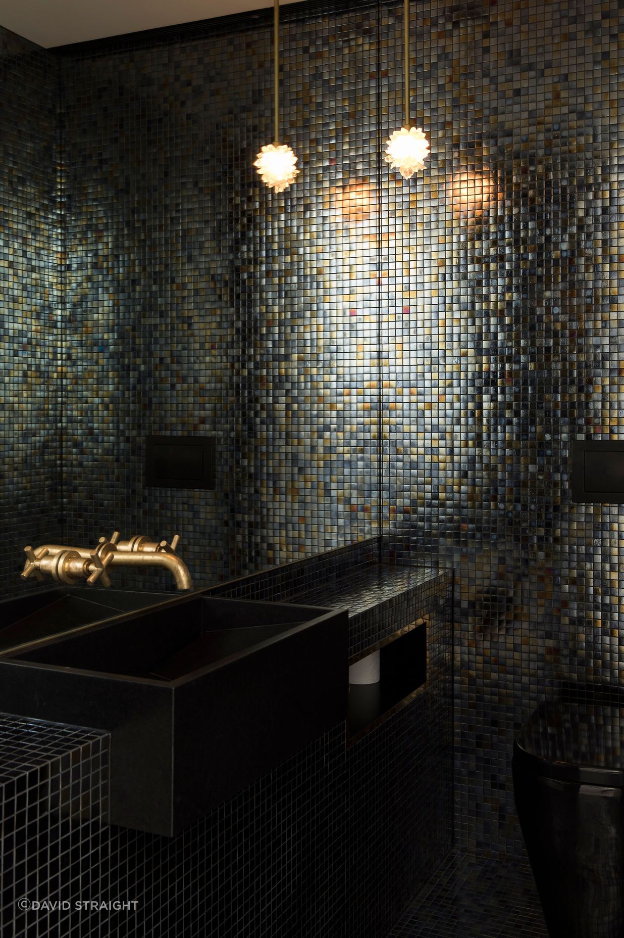 This dark and moody bathroom .features brass taps and black cabinetry.