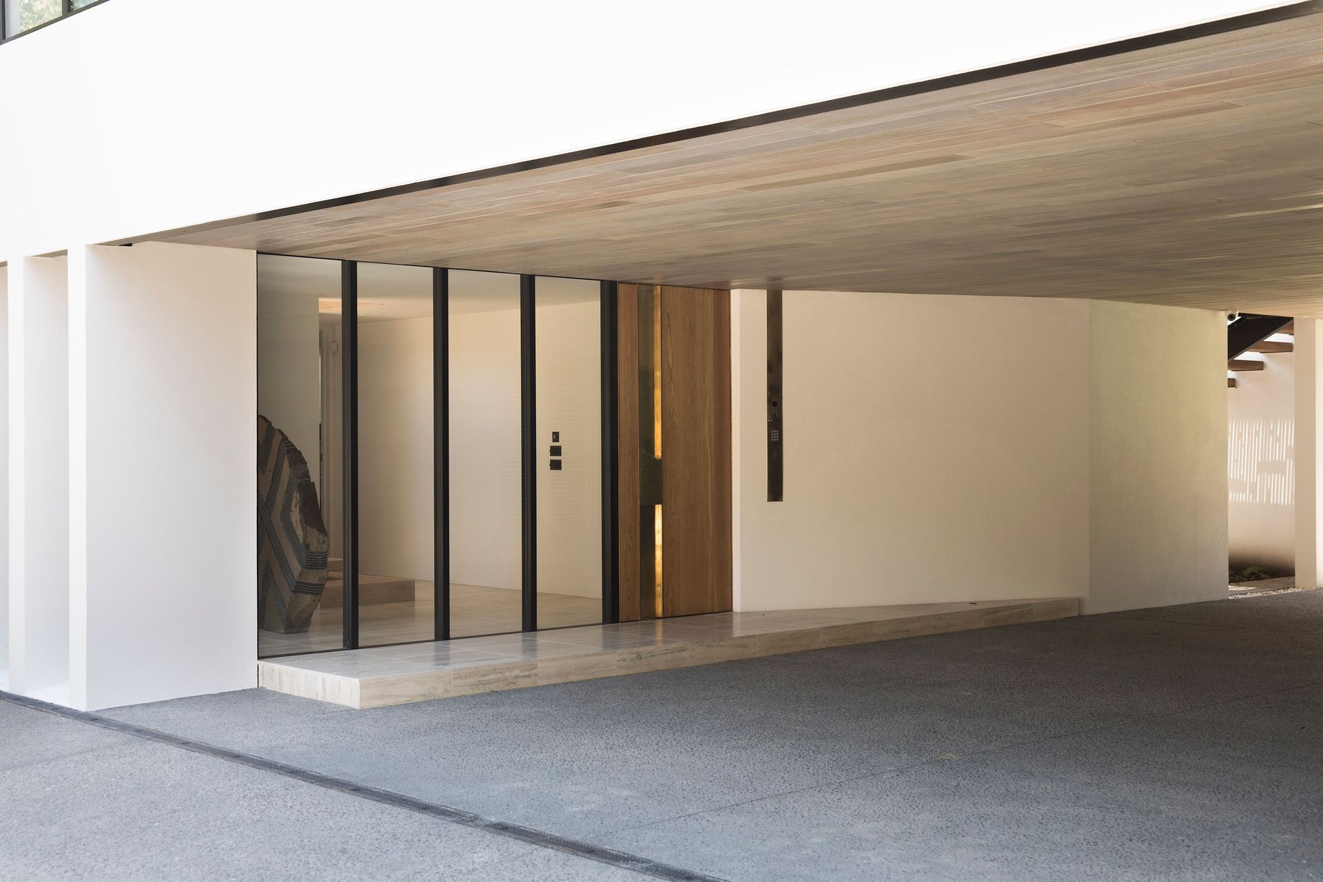 The entrance covered courtyard accesses the front entrance to the house, seen here, and a garage on the right, leading to a view of the neighbour's tennis court.