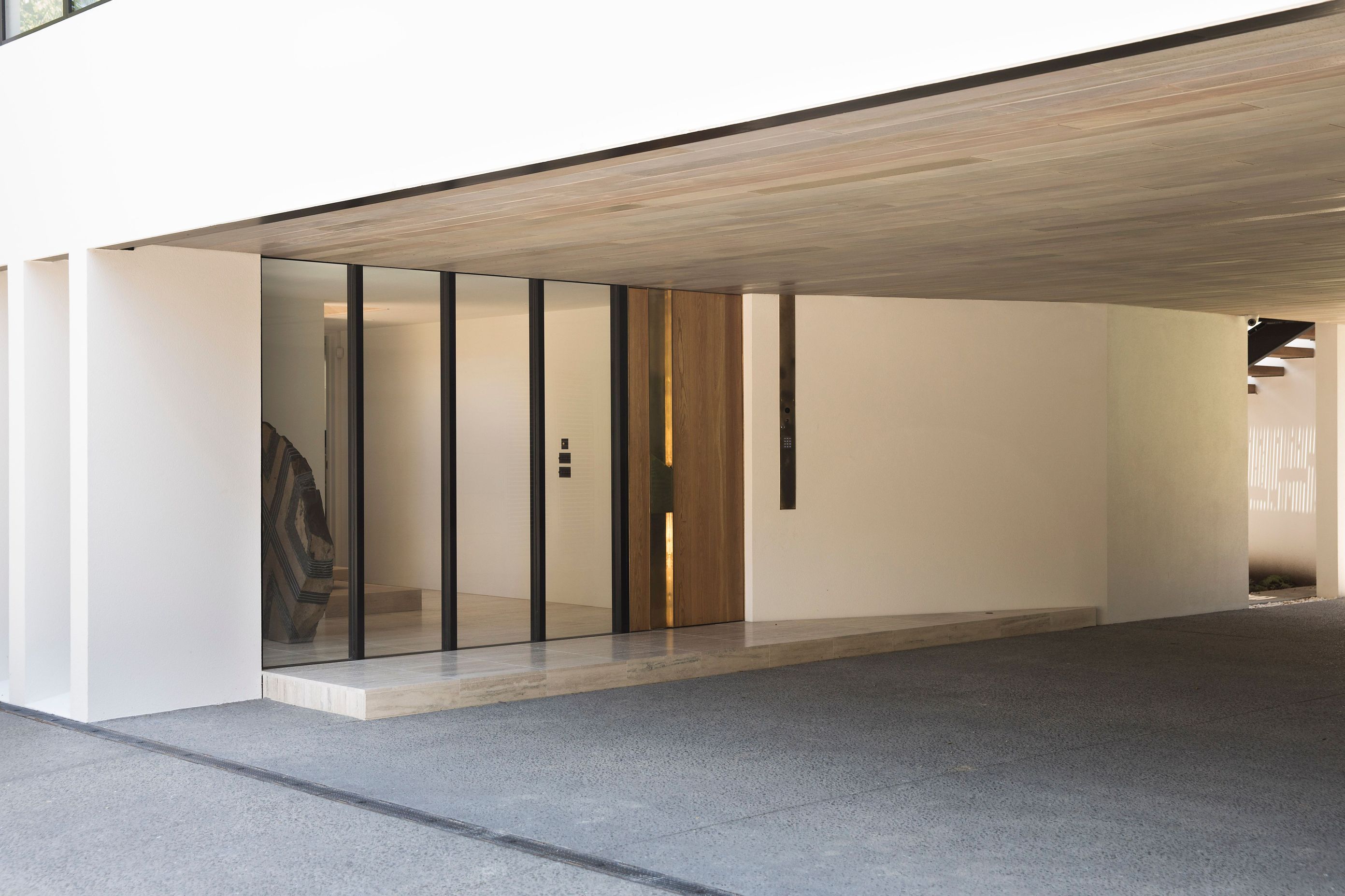 The entrance covered courtyard accesses the front entrance to the house, seen here, and a garage on the right, leading to a view of the neighbour's tennis court.