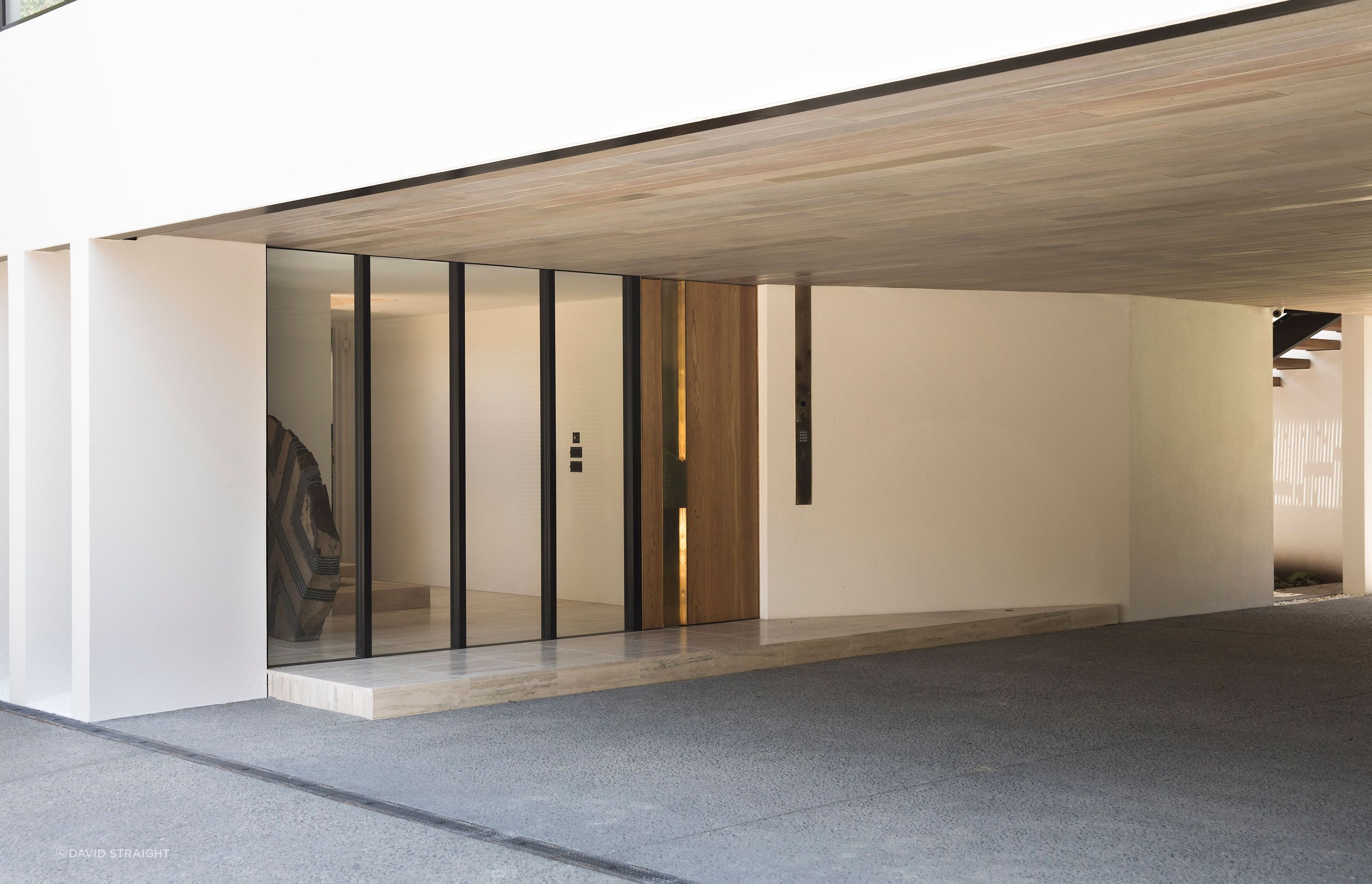 The entrance covered courtyard accesses the front entrance to the house, seen here, and a garage on the right, leading to a view of the neighbour's tennis court.