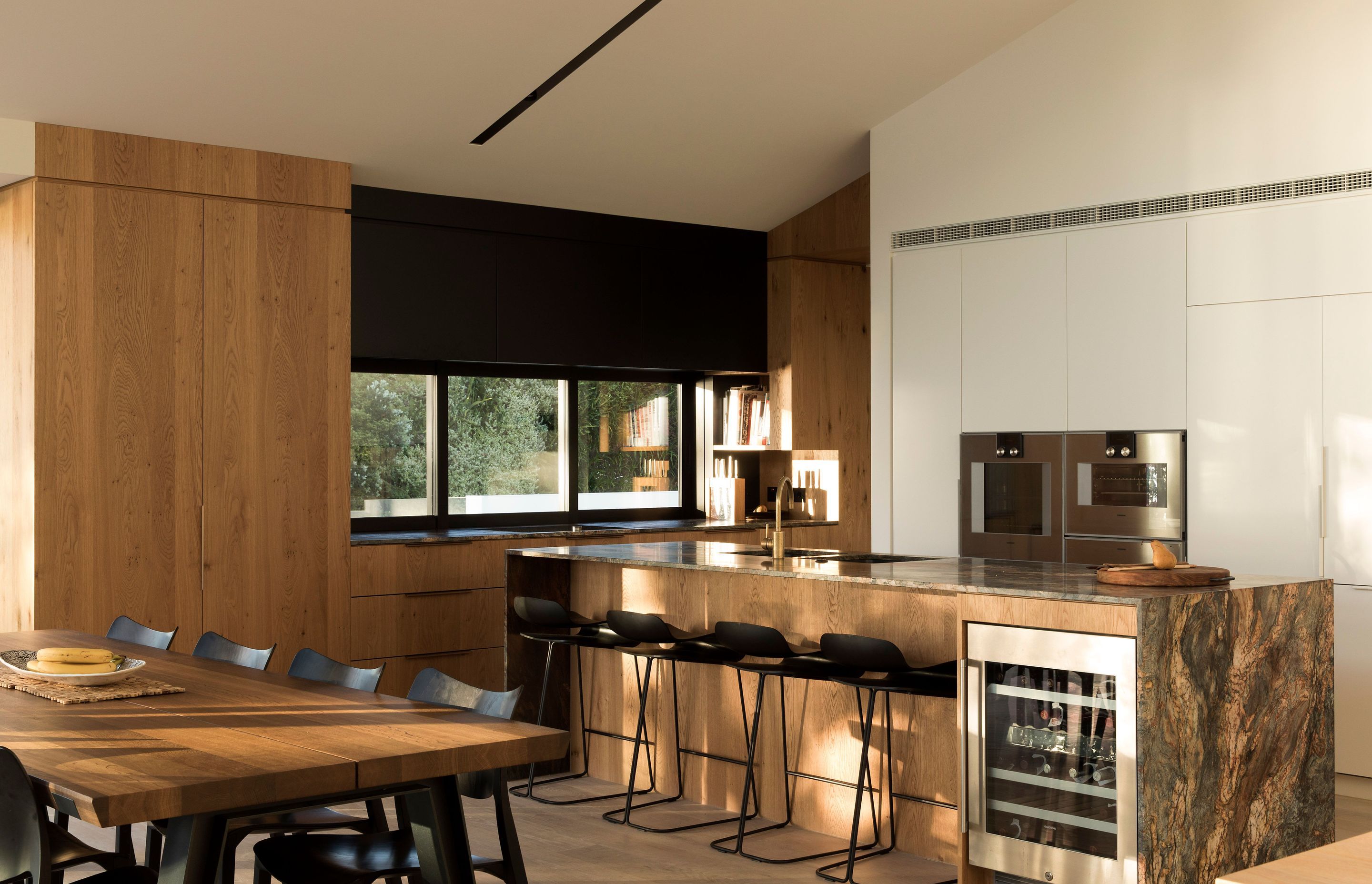 A natural material palette of timber, stone and brass, with black accents in the joinery and furnishings, are utilised throughout the home and are especially evident in the kitchen.