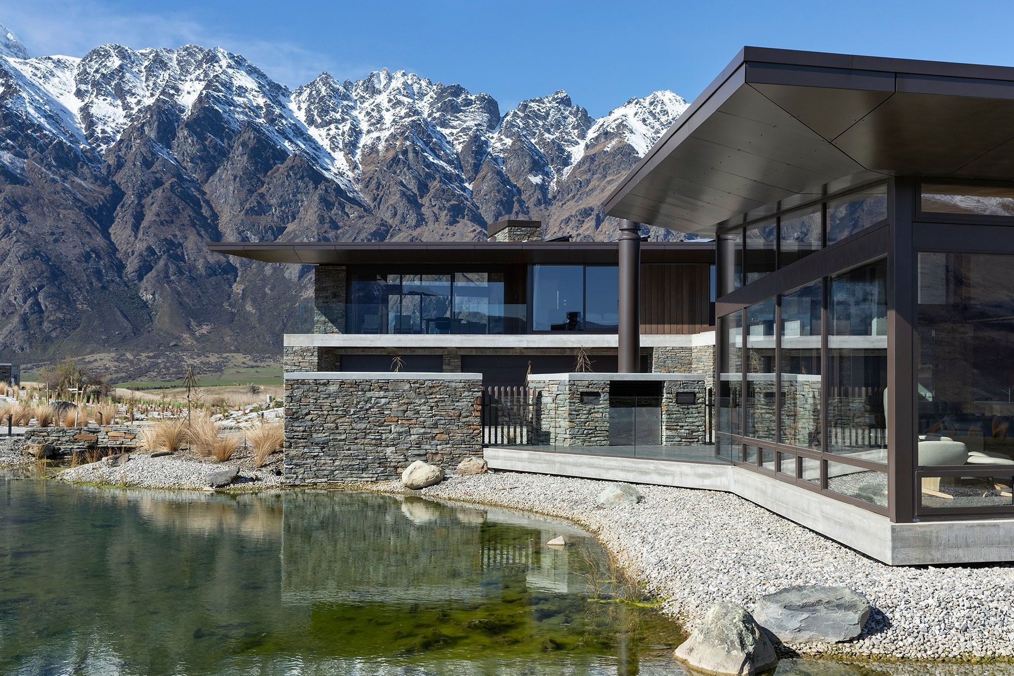 A natural tarn, or waterway, filters down to a manmade reflection pool below the house. A central courtyard with a fireplace is one of the sheltered outdoor areas around the house. SD.