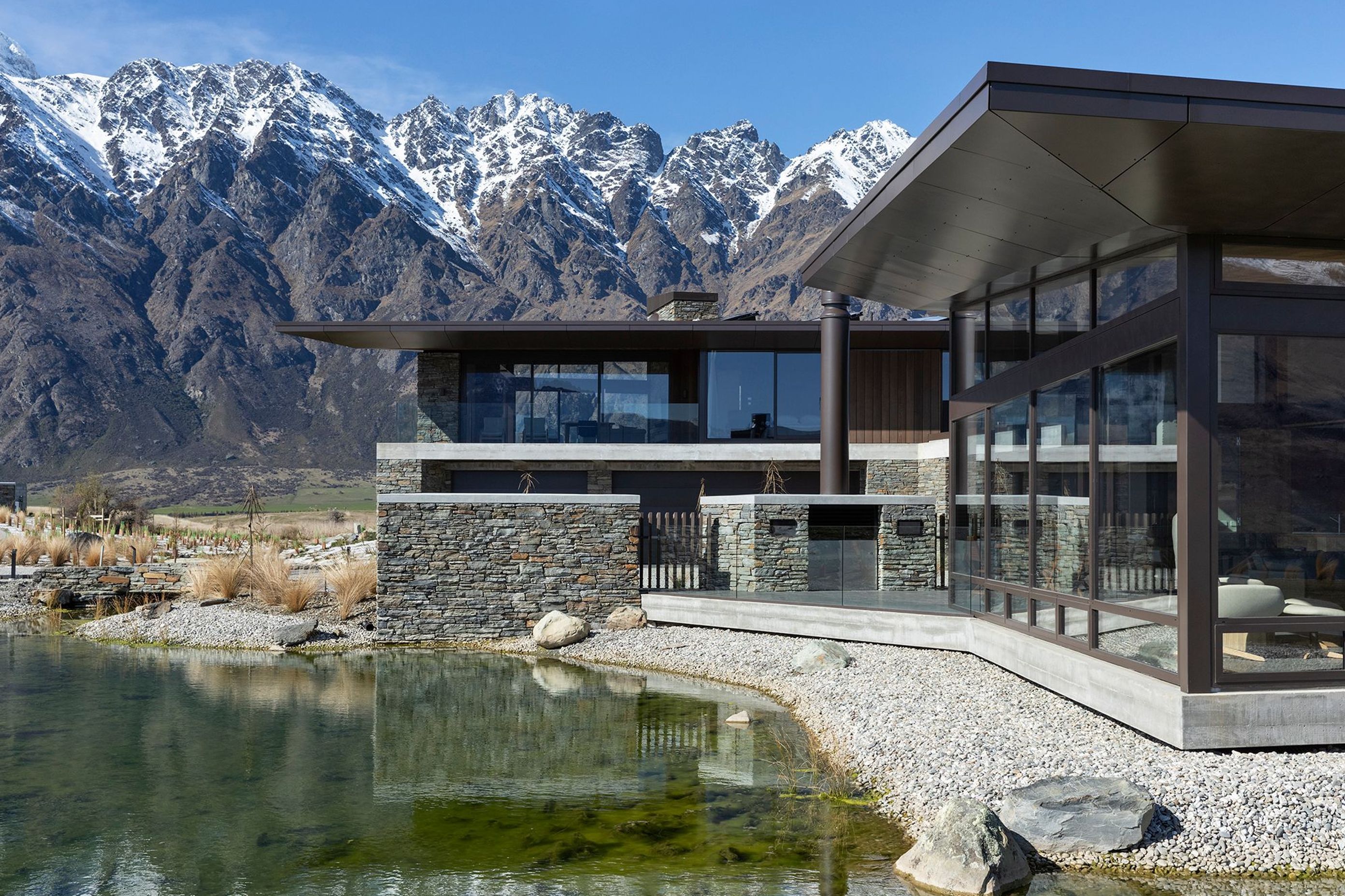 A natural tarn, or waterway, filters down to a manmade reflection pool below the house. A central courtyard with a fireplace is one of the sheltered outdoor areas around the house. SD.