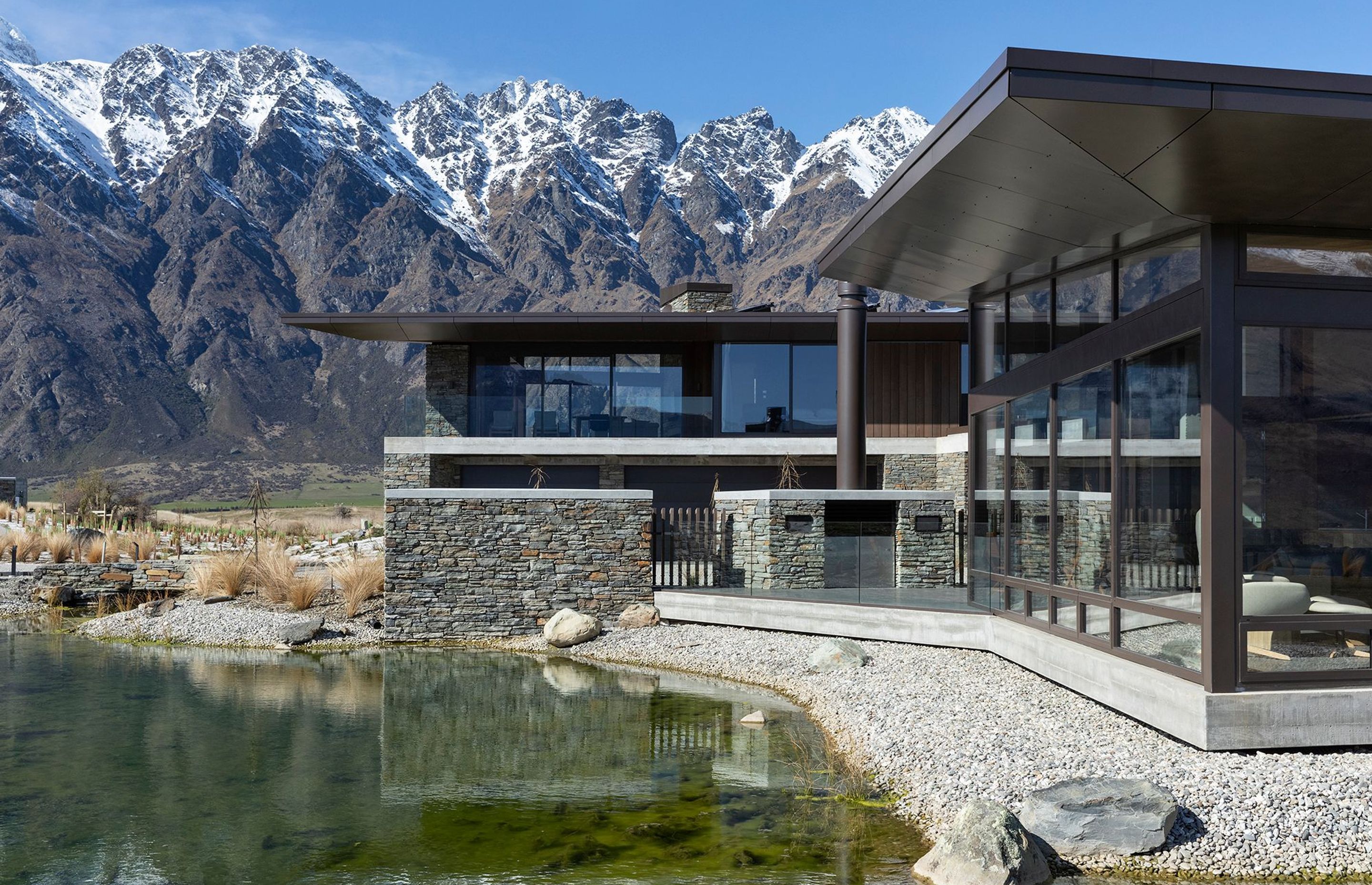 A natural tarn, or waterway, filters down to a manmade reflection pool below the house. A central courtyard with a fireplace is one of the sheltered outdoor areas around the house. SD.