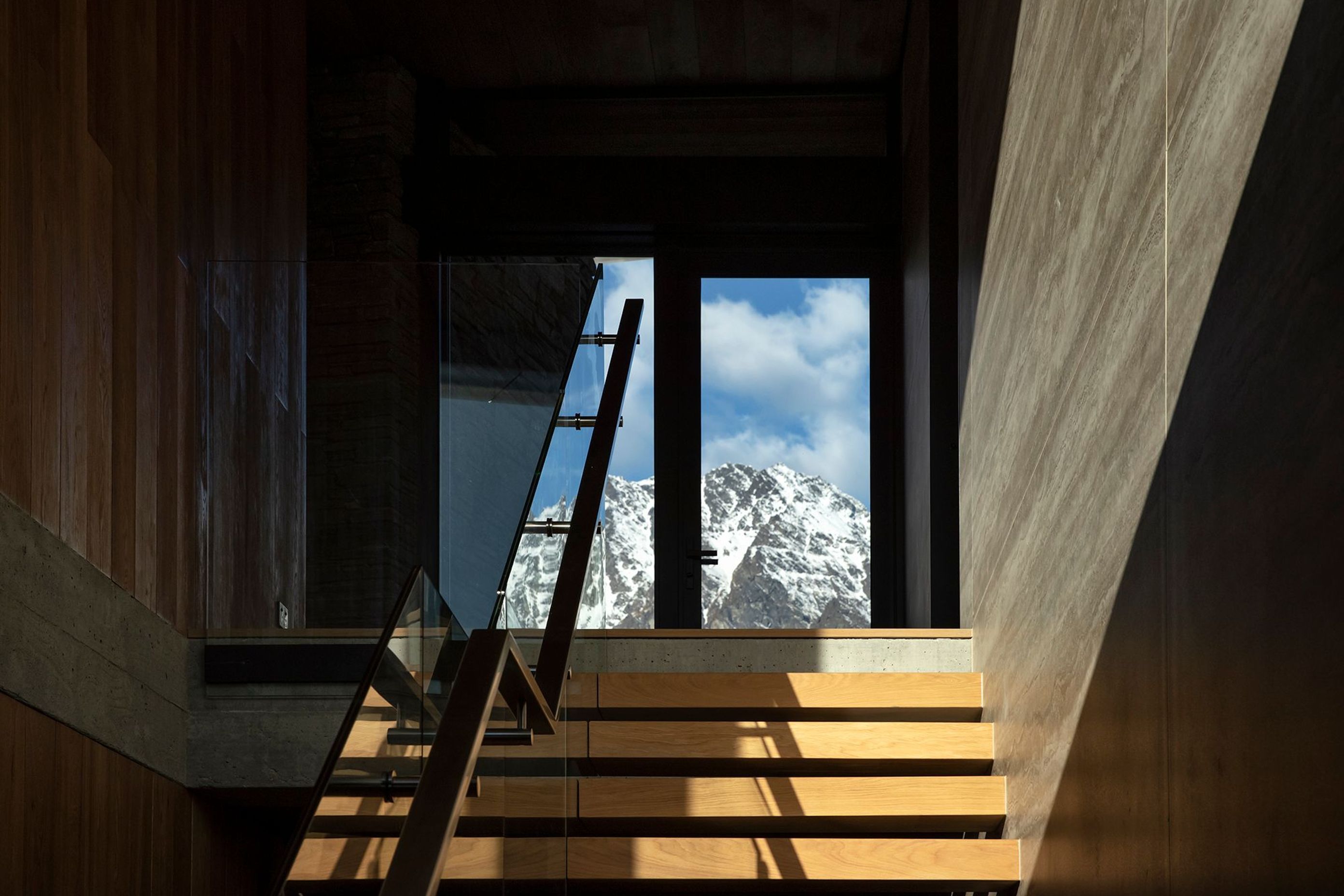 Floor-to-ceiling glazing at the top of the stairs reveals a view of The Remarkables, The staircase features matt-finished travertine panelling. Photograph: Simon Devitt.