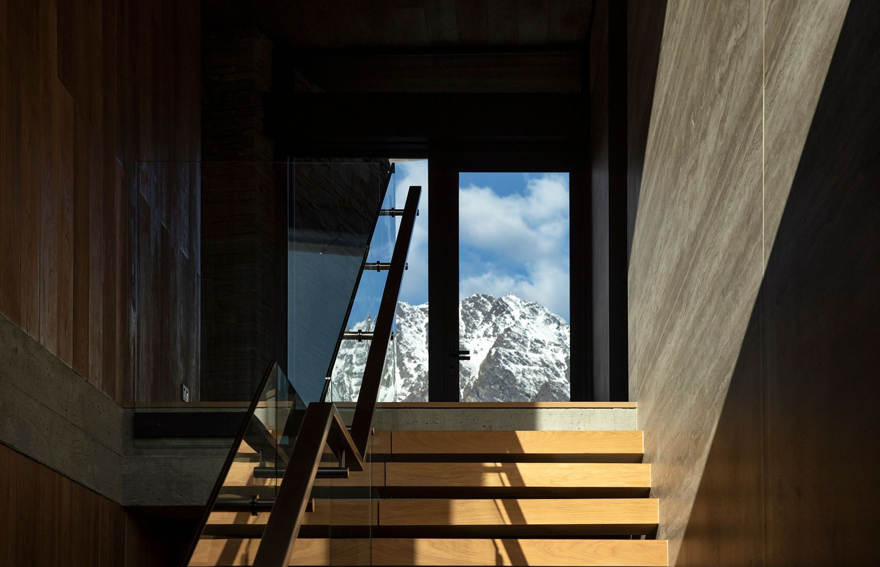 Floor-to-ceiling glazing at the top of the stairs reveals a view of The Remarkables, The staircase features matt-finished travertine panelling. Photograph: Simon Devitt.